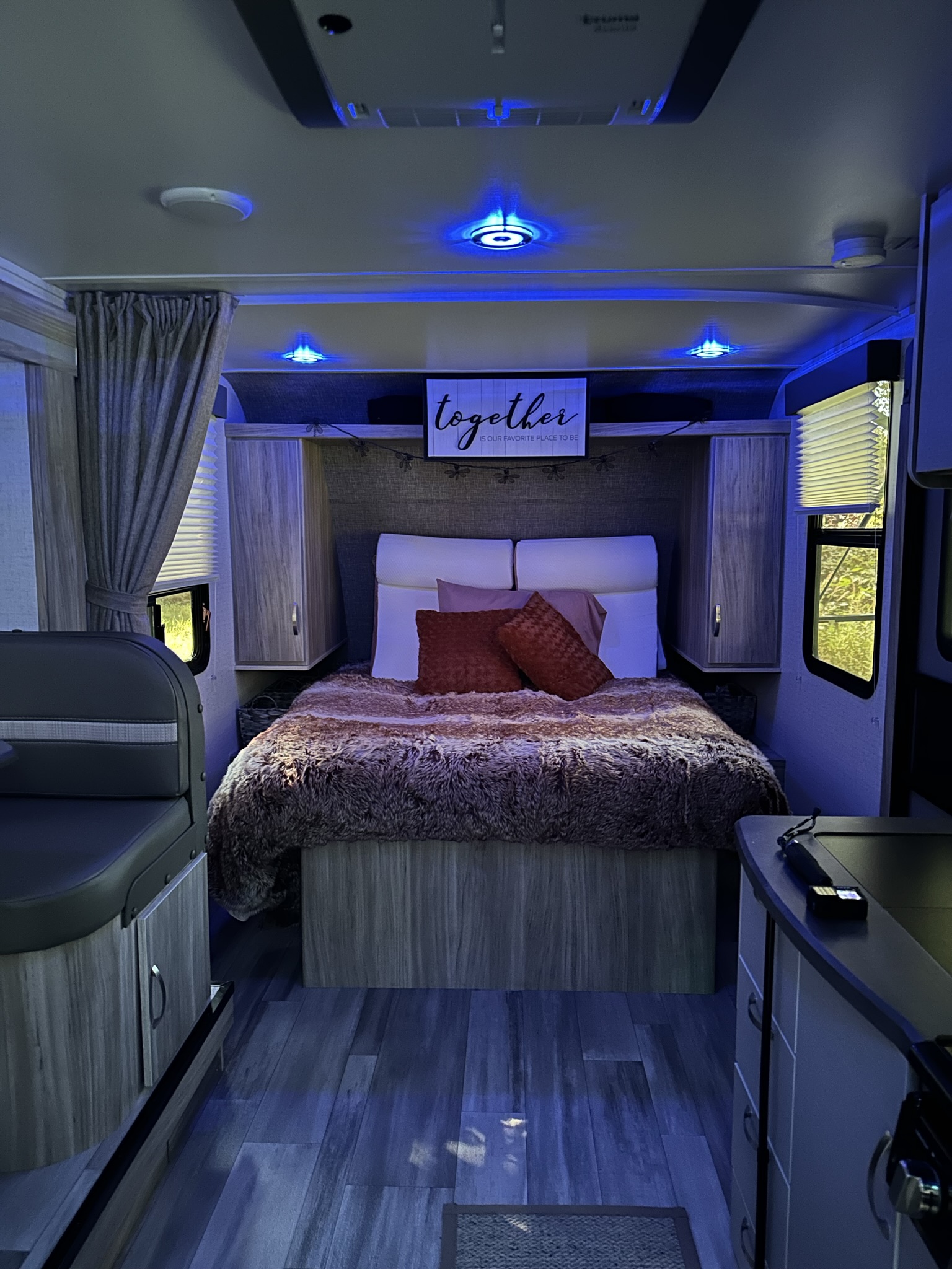 Cozy RV rental interior with ambient blue lighting, comfortable bed, and dinette area for relaxation.. Winnebago Micro Minnie FLX 2022