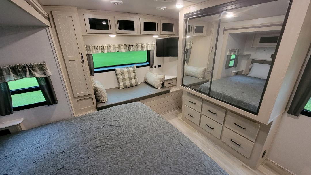 This RV rental's inviting interior includes a main bedroom, secondary lounge area with windows, and mirrored wardrobe.. Forest River Flagstaff Classic 2021