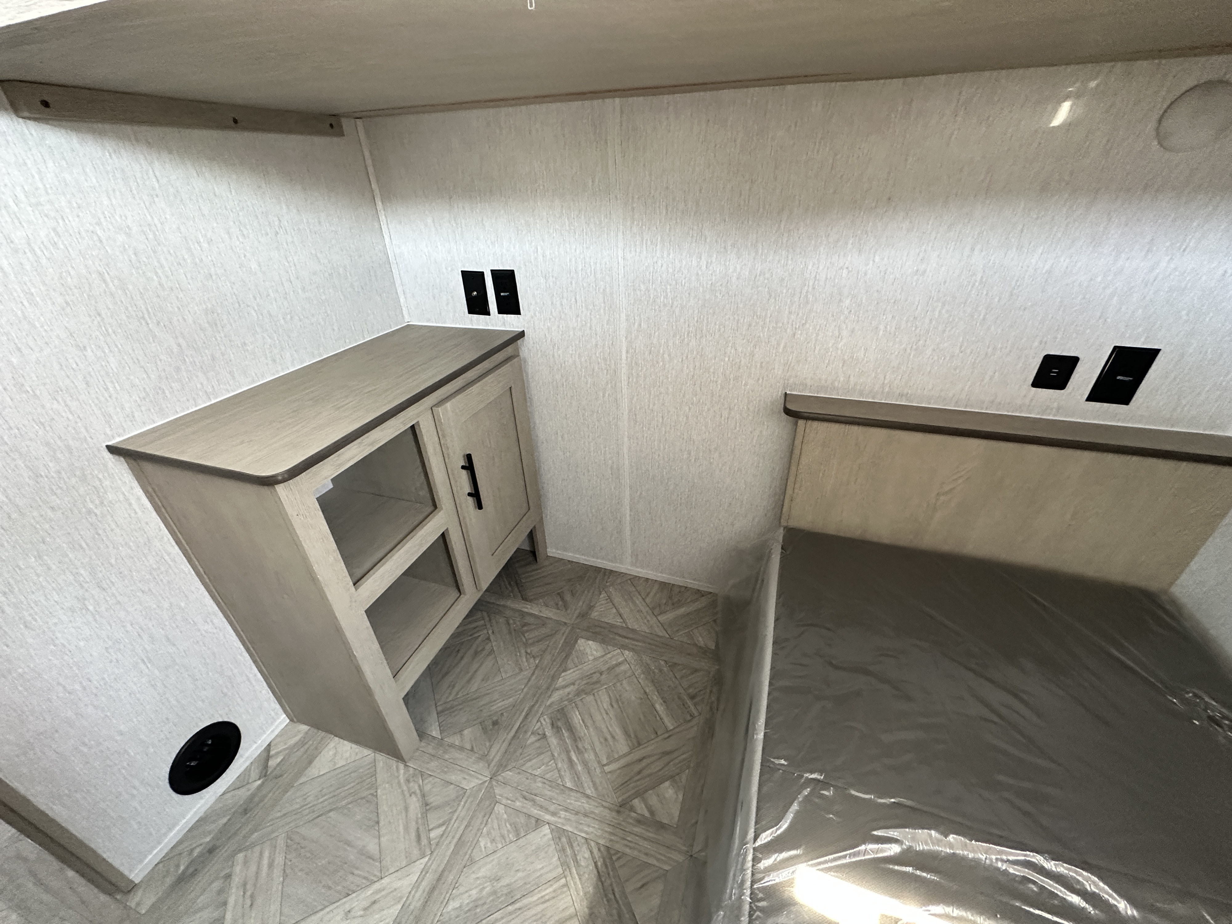 Bright RV rental interior features a cozy bed (wrapped), built-in storage cabinet, and stylish patterned flooring.. Forest River Salem Cruise Lite 2023