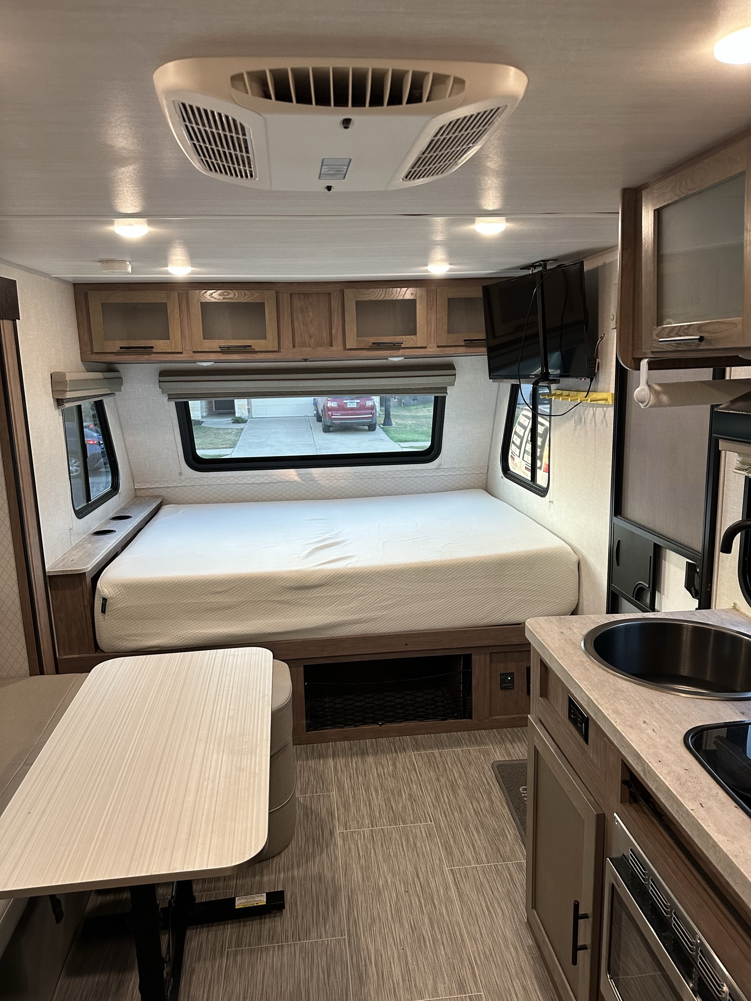 Bright rv rental interior featuring a comfortable bed, dinette, kitchen with sink, and overhead AC.. No Boundaries 19 2021