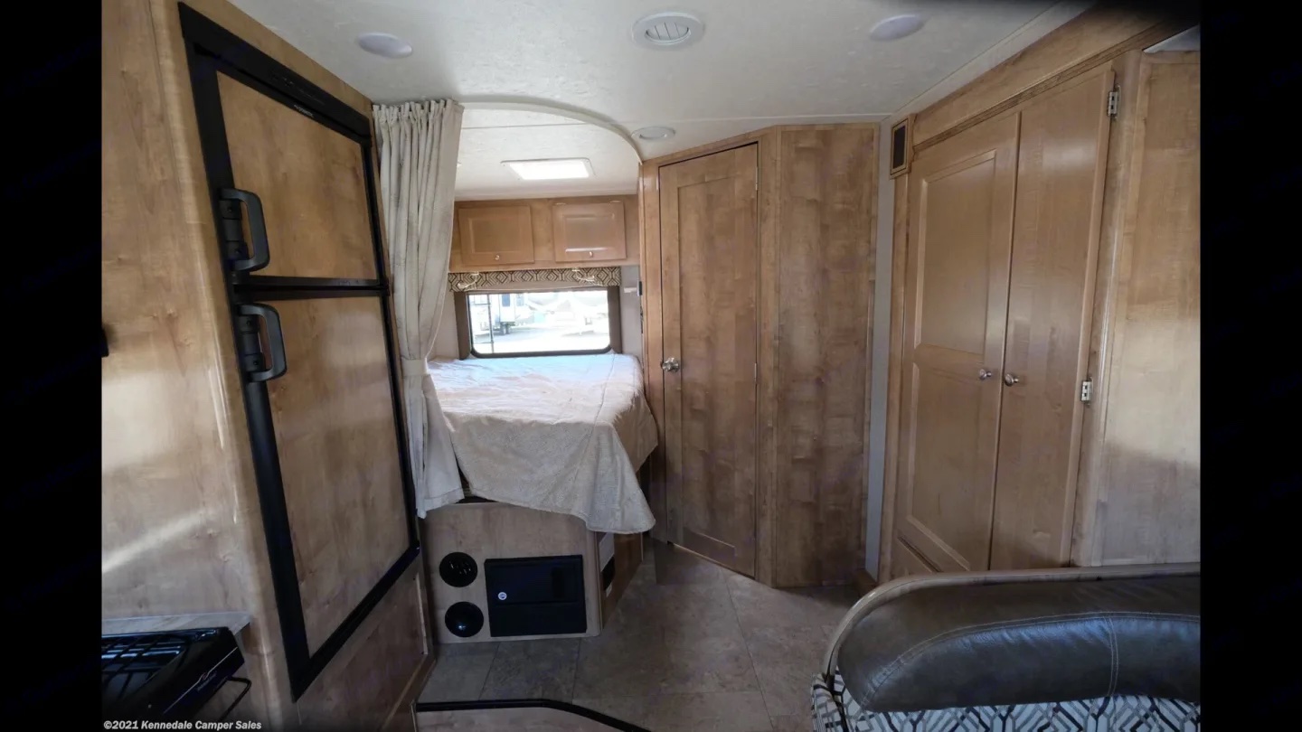 Explore this RV rental's inviting interior with a full bed, built-in fridge, and wooden cabinetry for your next adventure.. Coachmen Leprechaun 2020