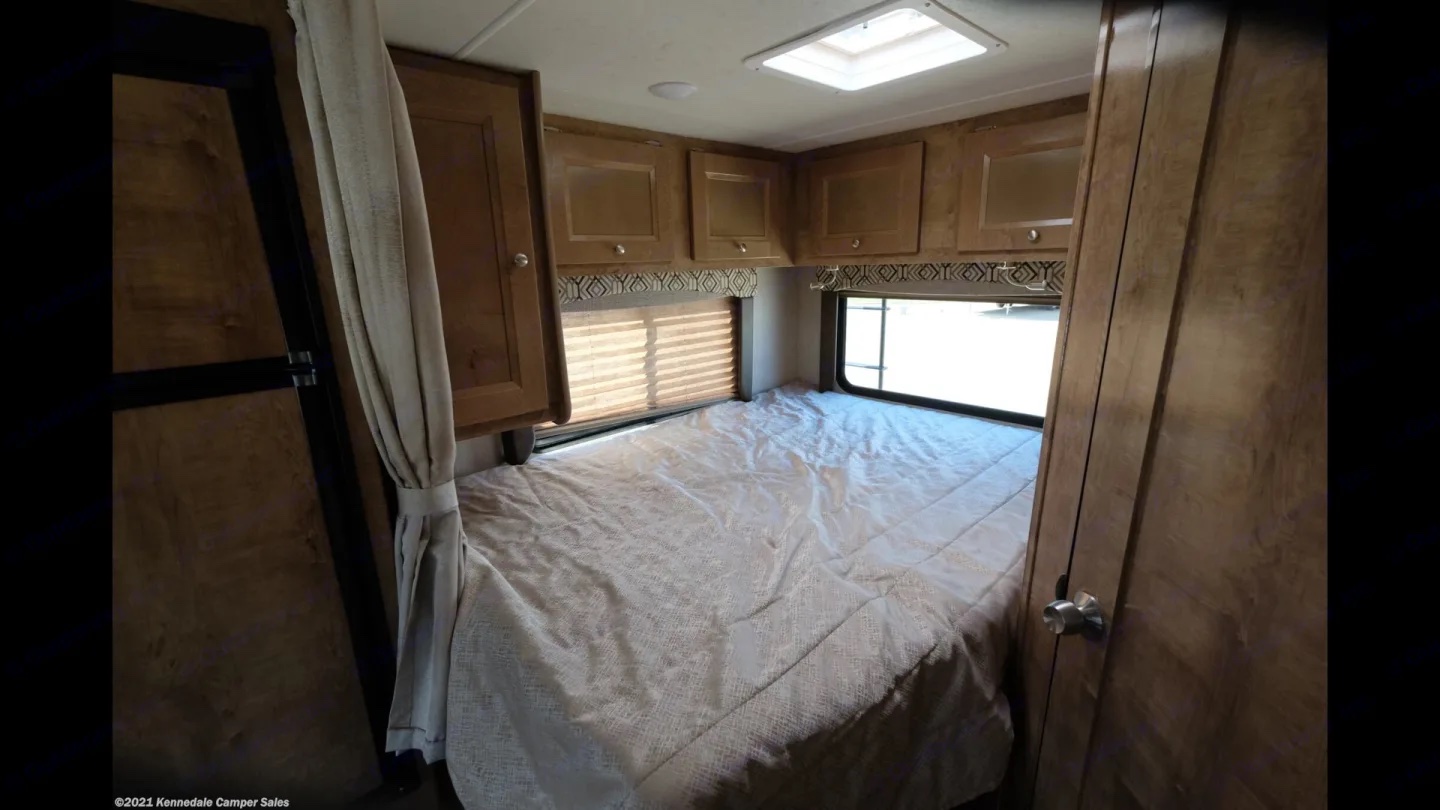 Spacious RV rental bedroom with a large bed, light wood cabinets, and two windows. Perfect for trips.. Coachmen Leprechaun 2020