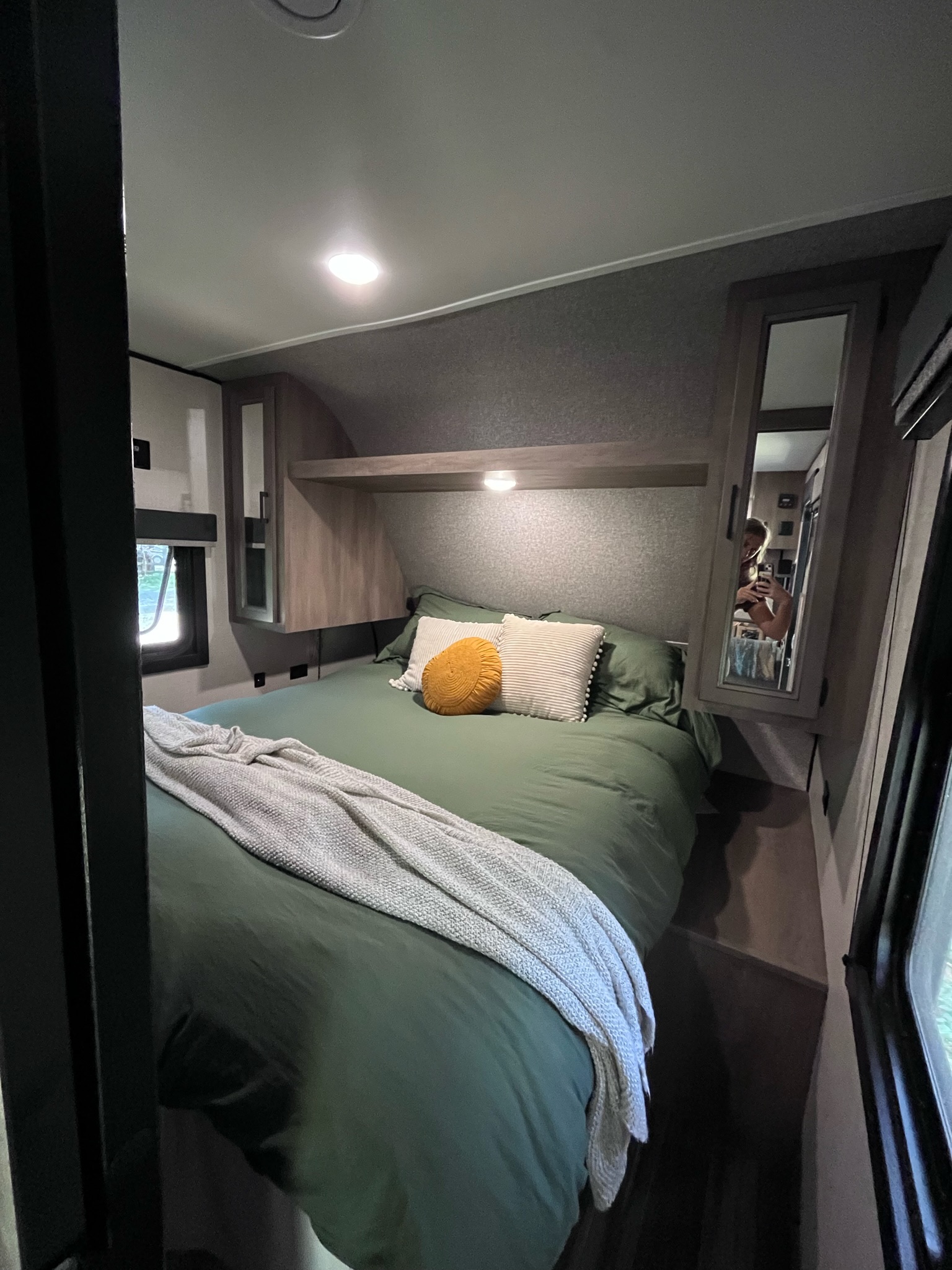 Inviting RV rental bedroom: green bed with pillows, throw blanket, window, and overhead light for comfortable travel.. Highland Ridge RV Open Range 2022