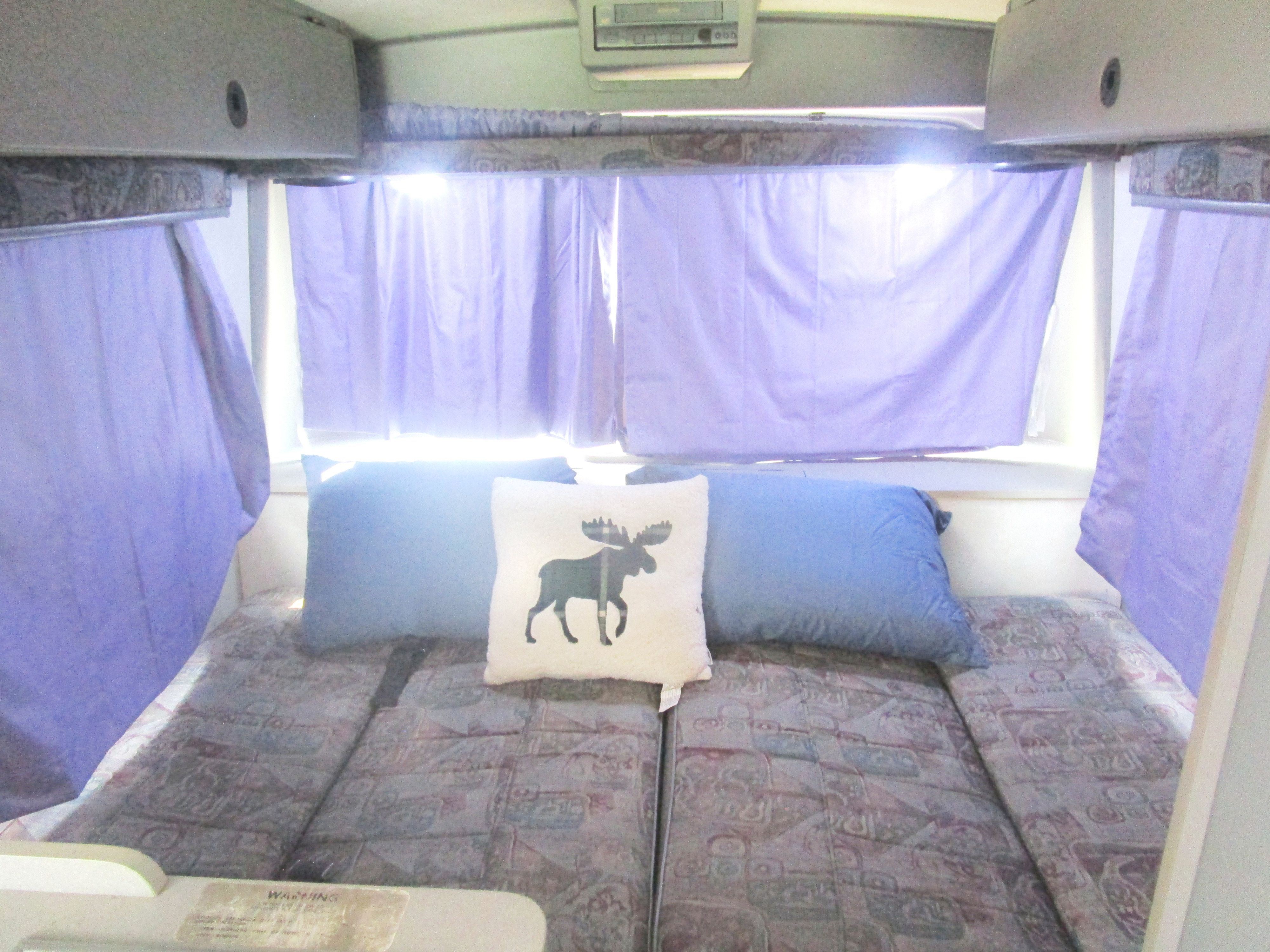 Rialta sleeping area with fold-down seats folded down and back and side curtains drawn.. Winnebago Rialta 1997