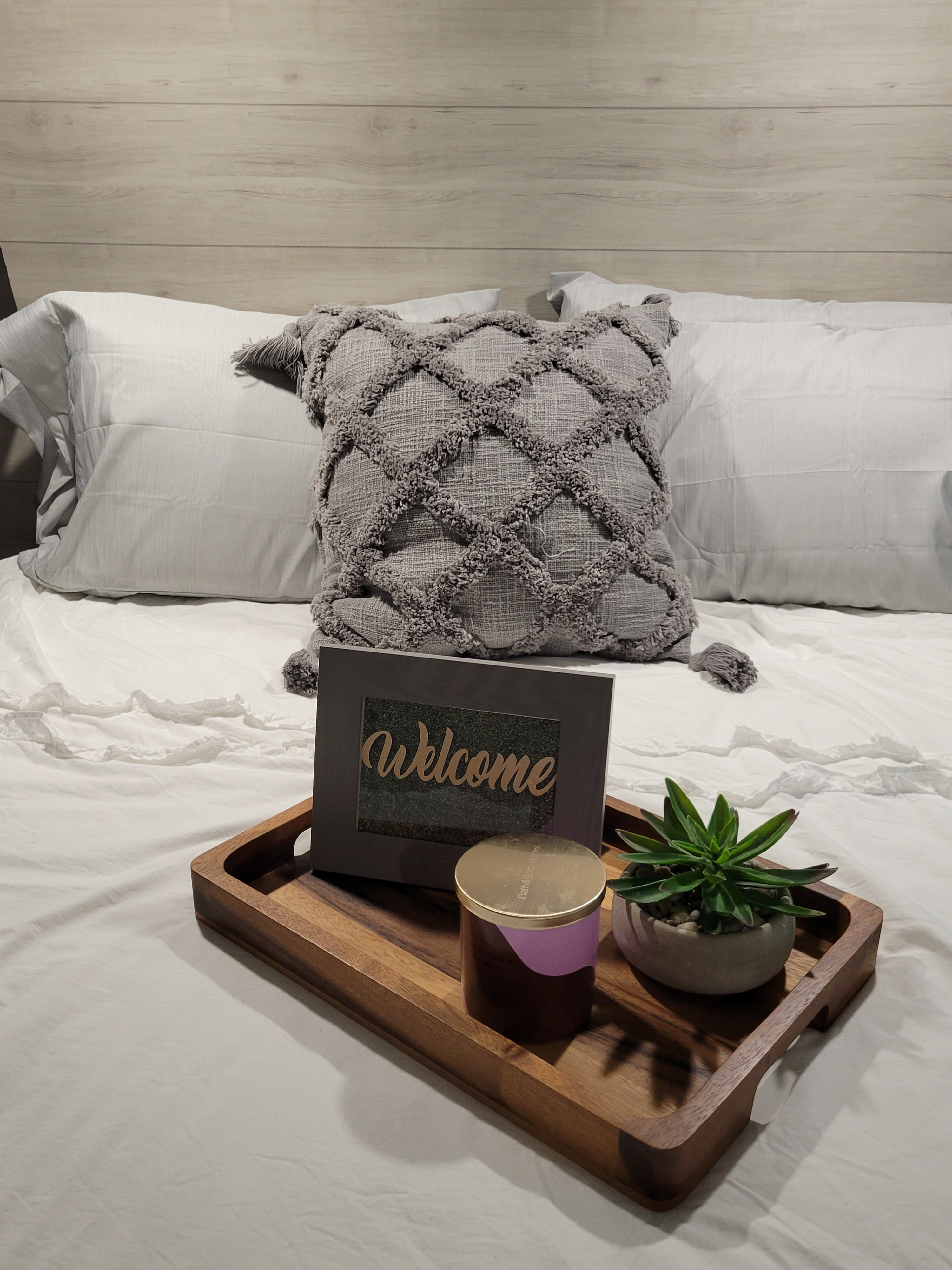 Welcome to your comfortable RV rental! Bed with textured pillow, wooden tray, candle & plant create a cozy vibe.. Jayco Jay Flight 2023