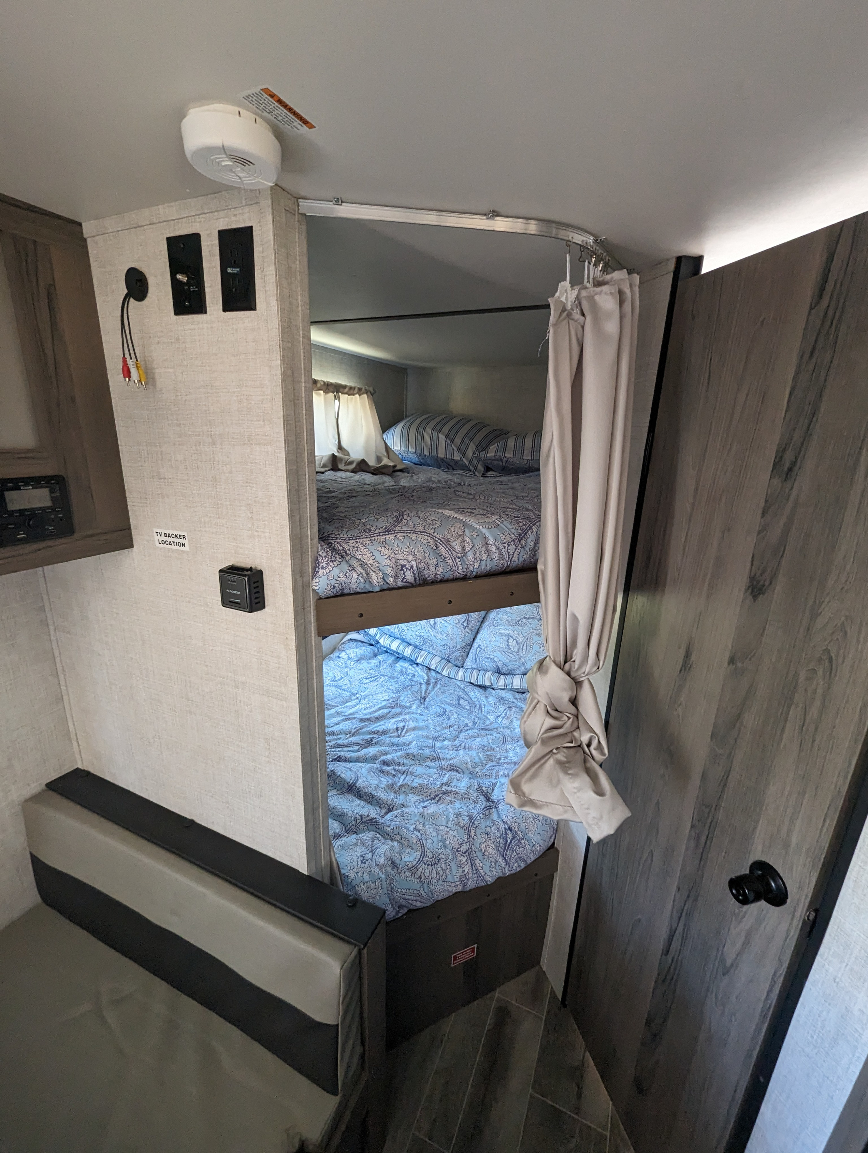 Inside an rv rental: functional bunk beds with blue bedding, a cozy bench, TV connections, and a smoke detector.. Gulf Stream Other 2021
