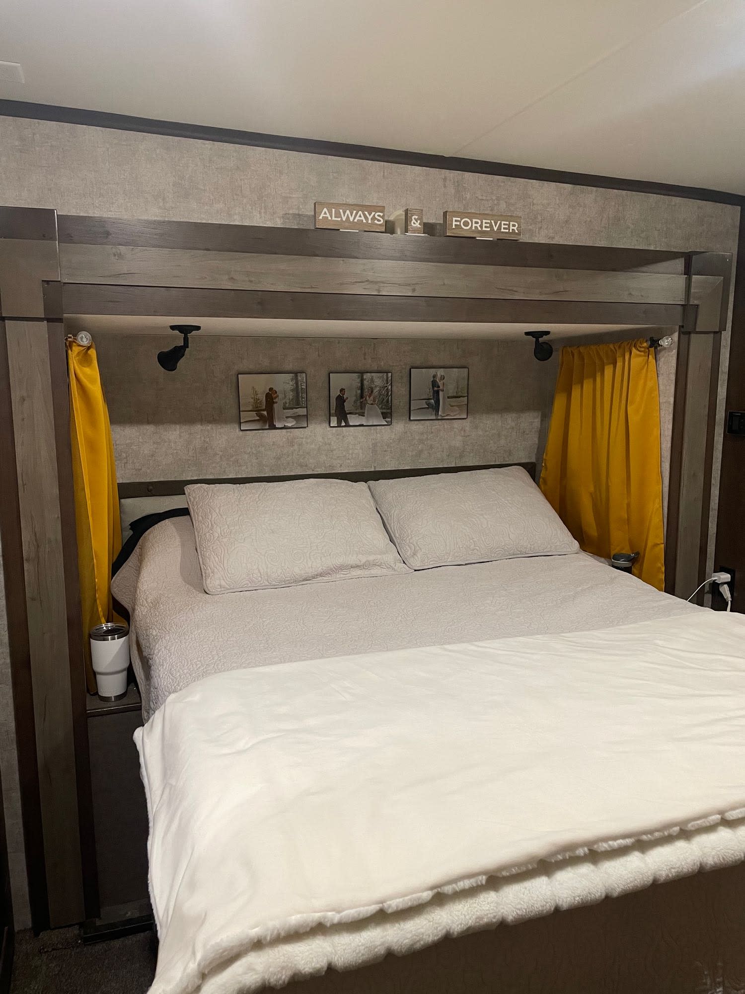 Cozy RV rental bedroom interior featuring a comfortable bed, personal photos, and yellow curtains. Perfect for your next trip!. Highland Open Range 2017