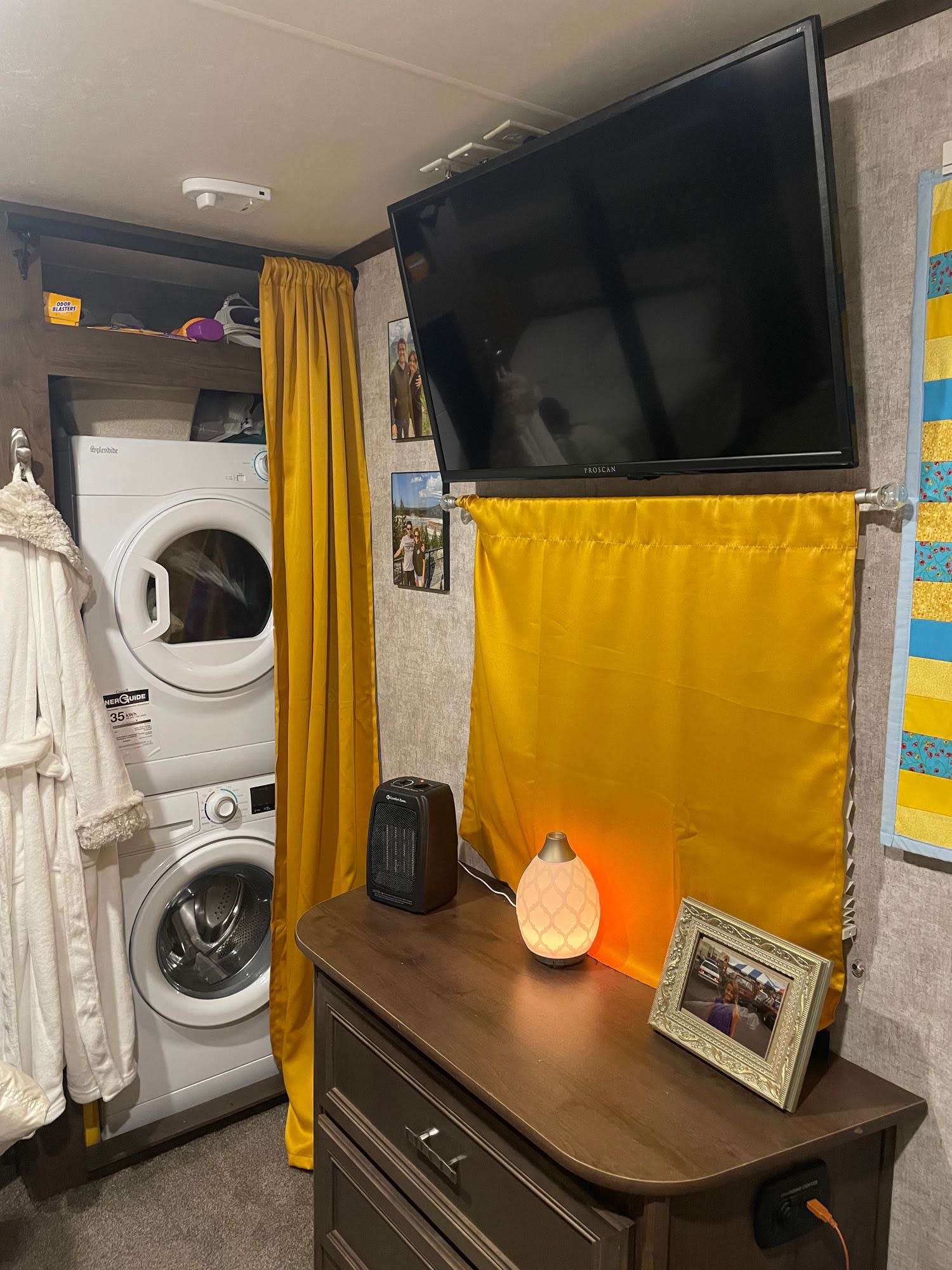 Cozy RV rental interior with stacked washer/dryer, wall-mounted TV, dresser, and decor.. Highland Open Range 2017