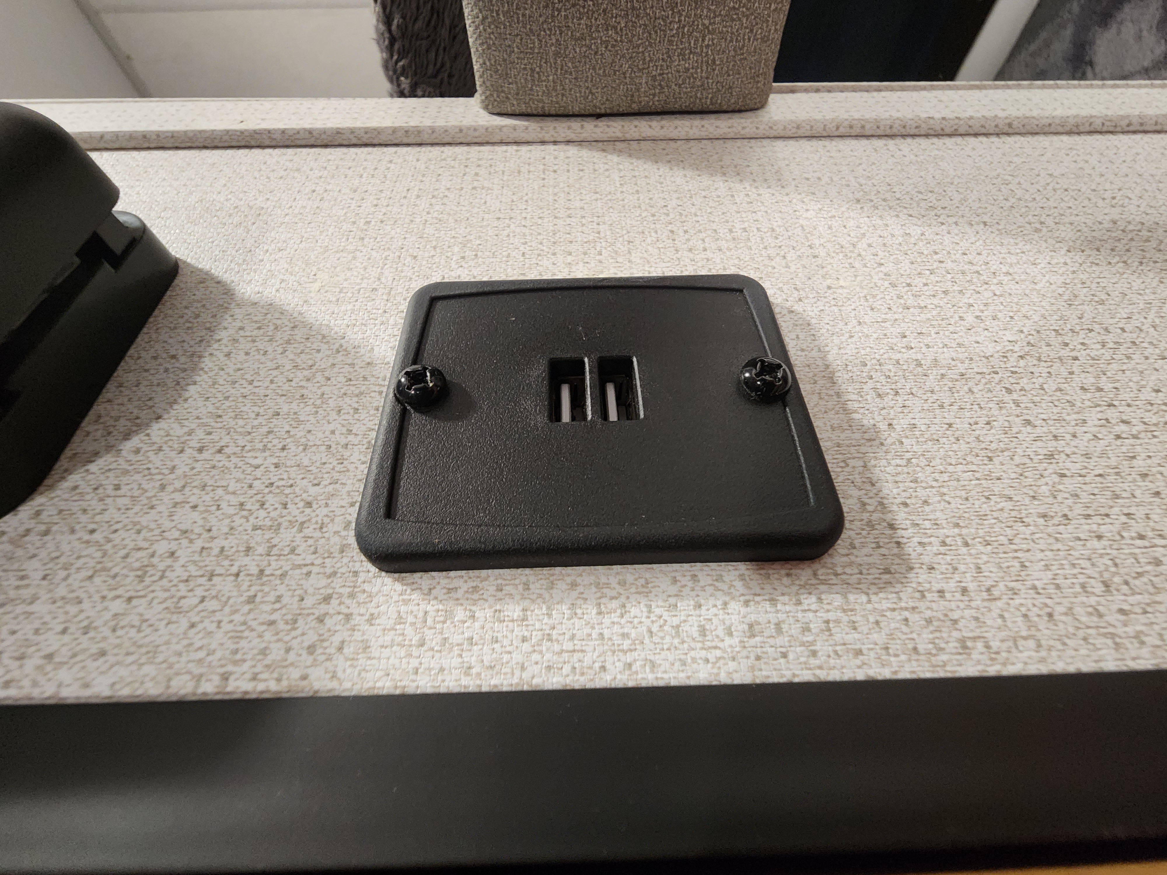 Black plastic RV rental mounting base with screws on a textured counter. Likely for secure TV setup in an RV interior.. Avenger LT 2022