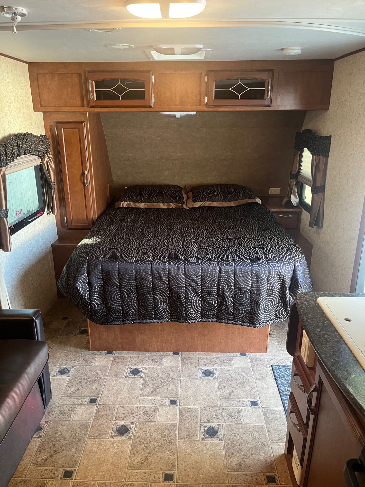 This RV rental offers a compact and comfortable bedroom with a queen bed, decorative quilt, and ample storage.. Winnebago Other 2013