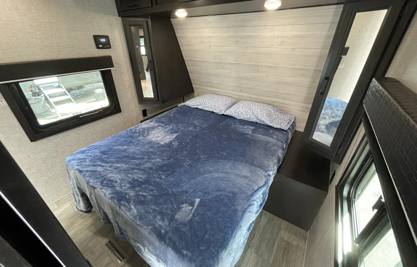 Comfortable RV rental bedroom with a bed featuring blue bedding, a window for views, and built-in storage. Perfect for your next trip.. Jayco Jay Flight 2022