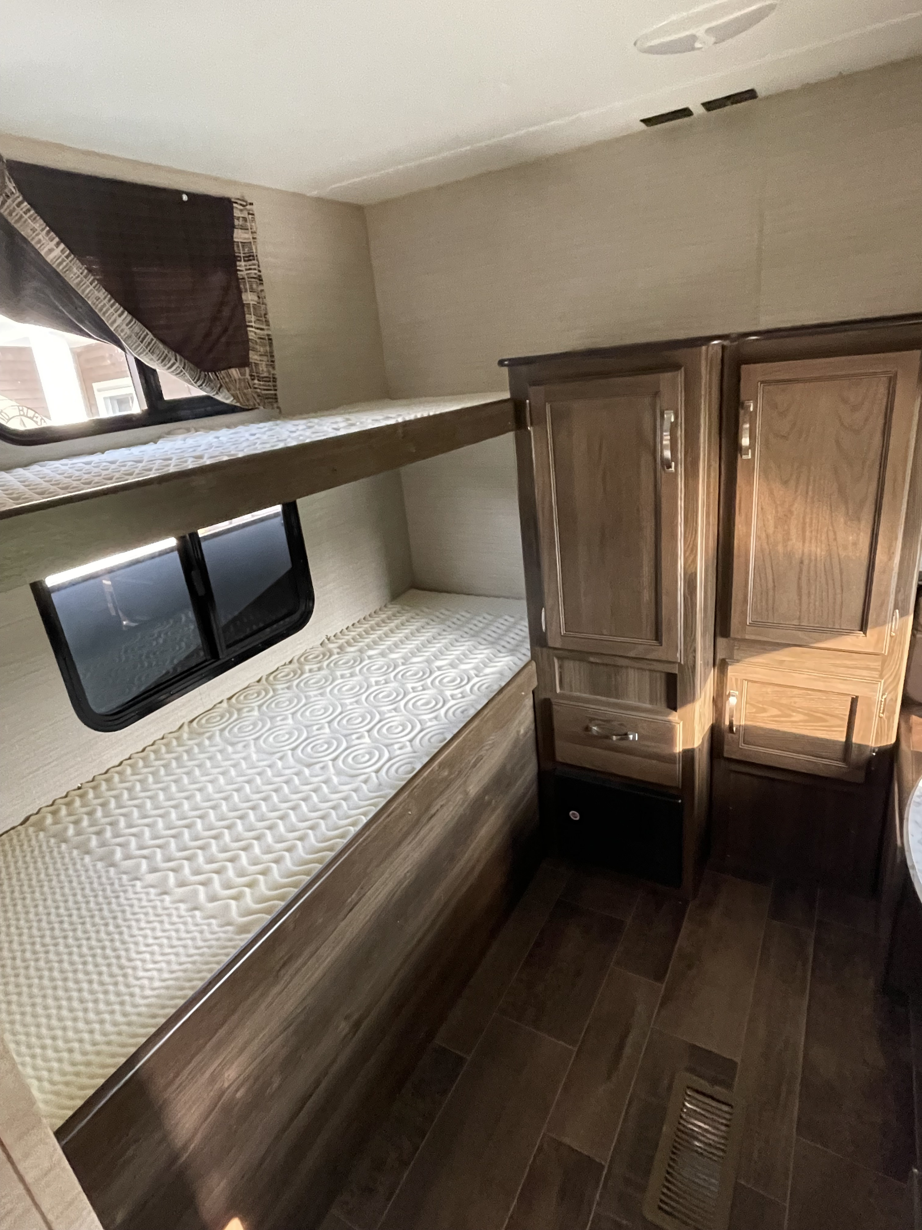 RV rental interior featuring cozy bunk beds with windows and built-in storage cabinets for a comfortable stay.. Keystone RV Bullet Ultra Lite 2018