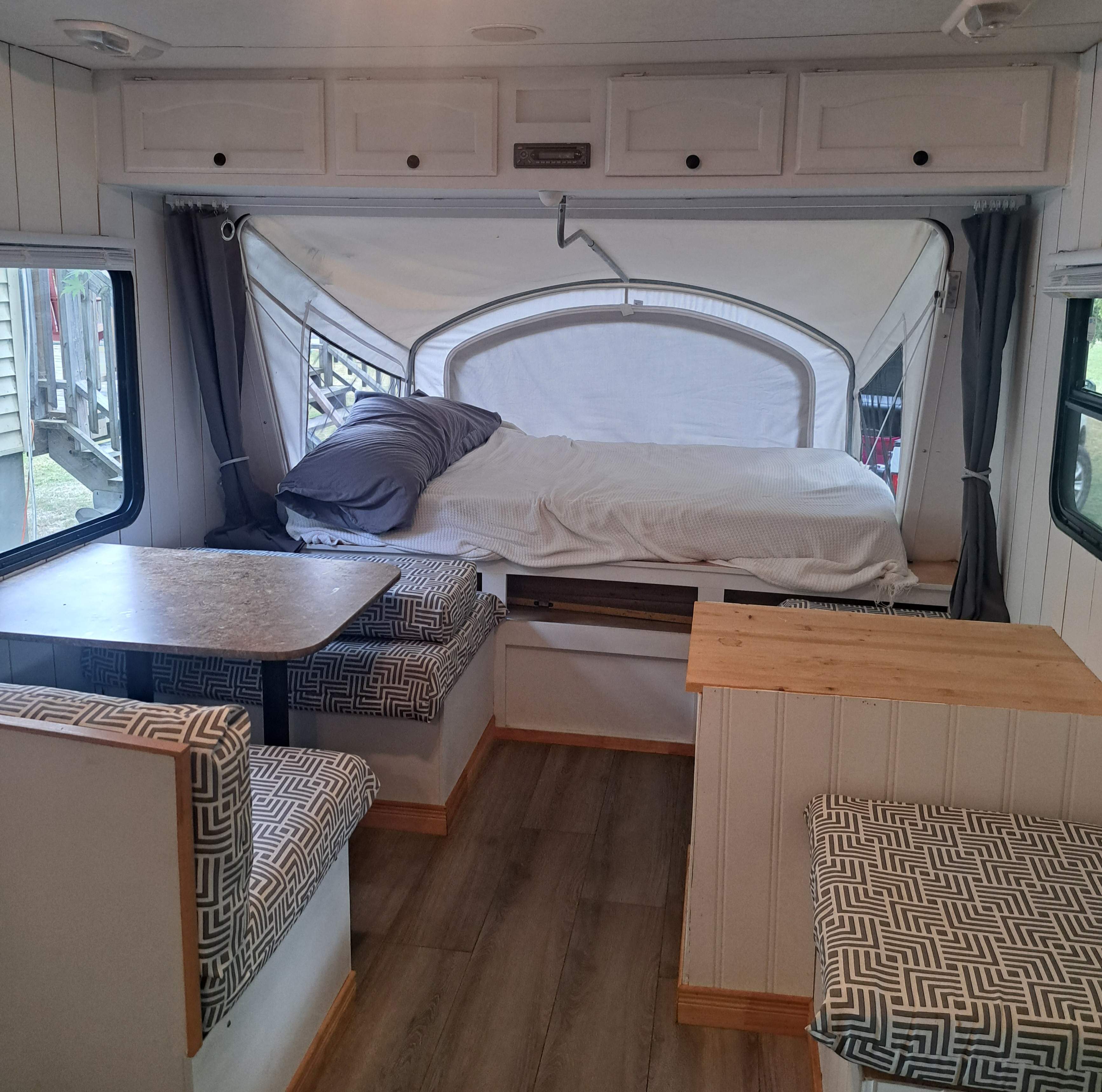 Cozy RV rental interior: features a pop-out bed, dinette with patterned cushions, and renovated white cabinets.. Other Other 2008