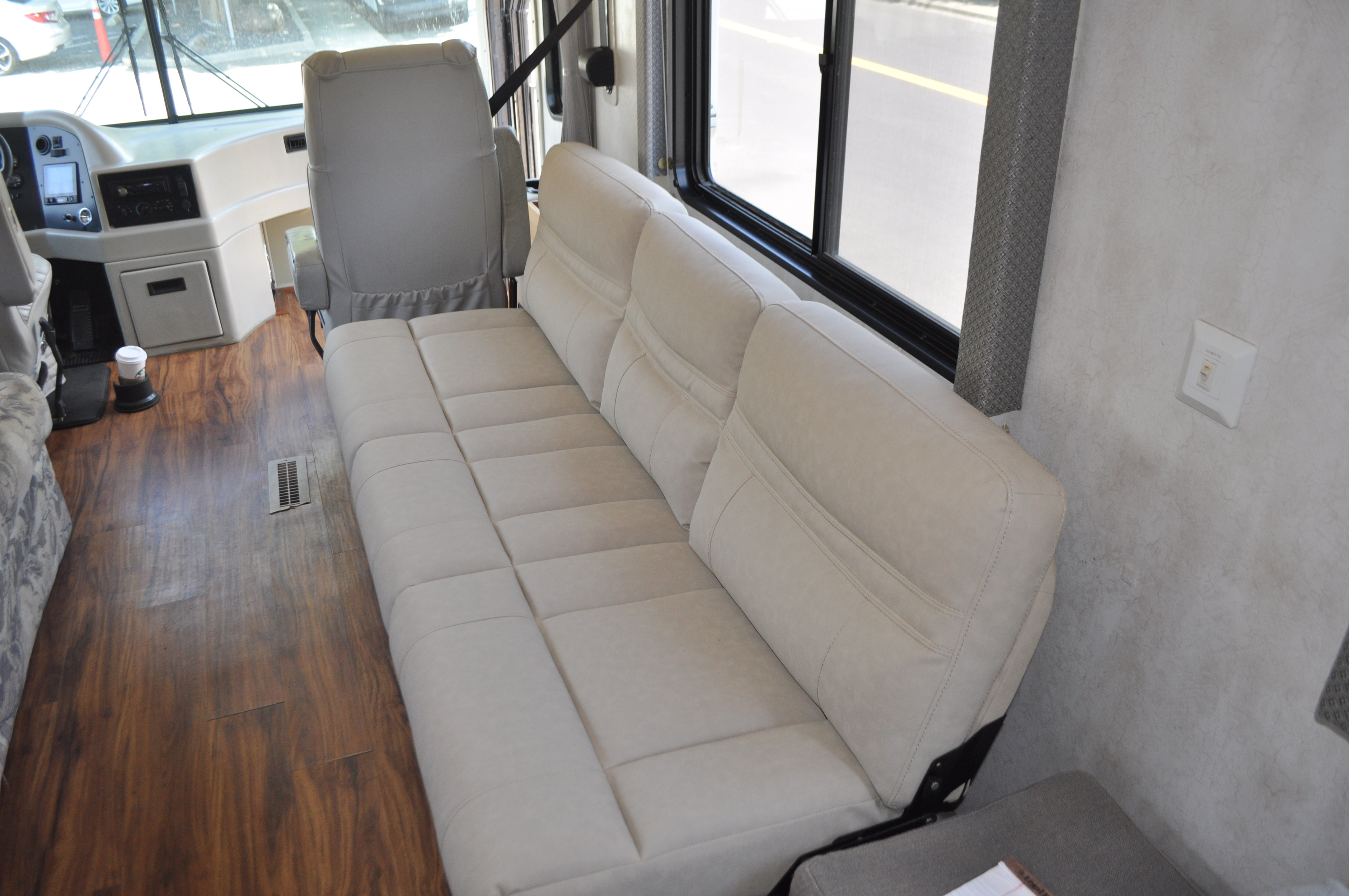Spacious RV rental interior featuring a light-colored sofa, hardwood flooring, and a clear view of the cockpit.. Holiday Rambler Endeavor 2000