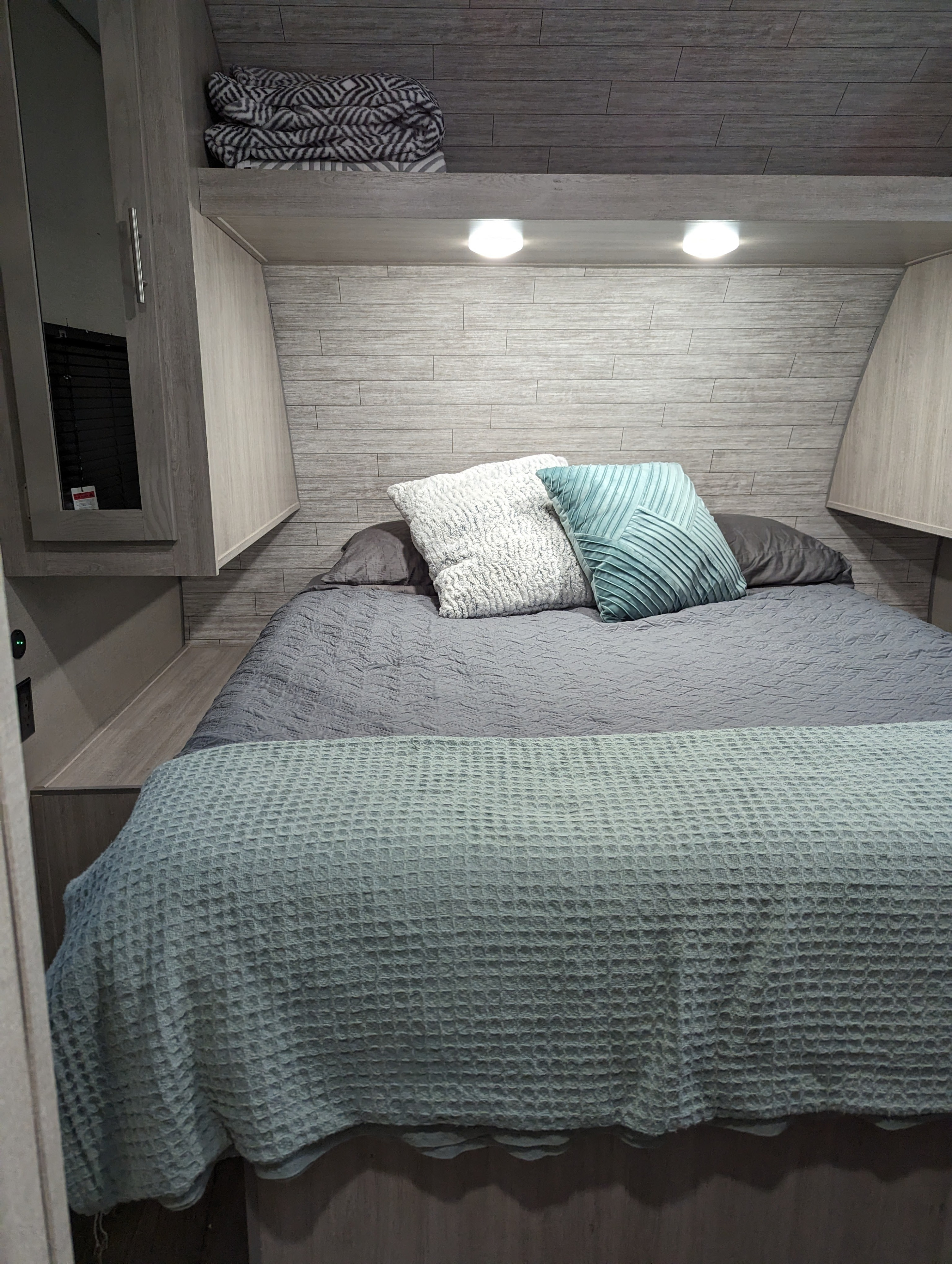 Cozy RV rental bedroom featuring a comfortable bed with decorative pillows, and overhead storage with lights.. Coachmen Catalina Summit 271DBS 2023