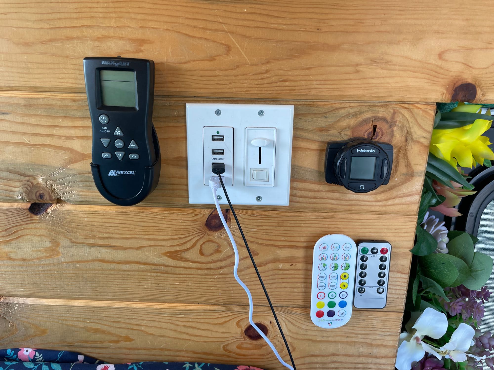 RV rental comfort controls: Maxx Air fan, Webasto heater, USB charging, and light remotes on a wood panel.. Dodge 1500 Ram Promaster (Highroof) 2019