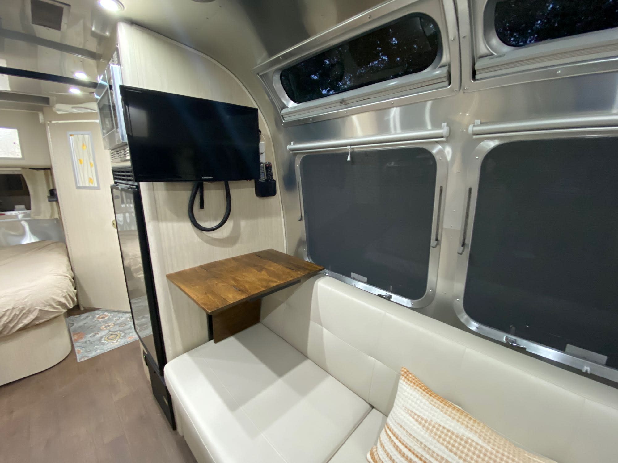 Sleek Airstream RV rental interior with polished aluminum, TV, sofa, small table, and bedroom view.. Airstream International 2016