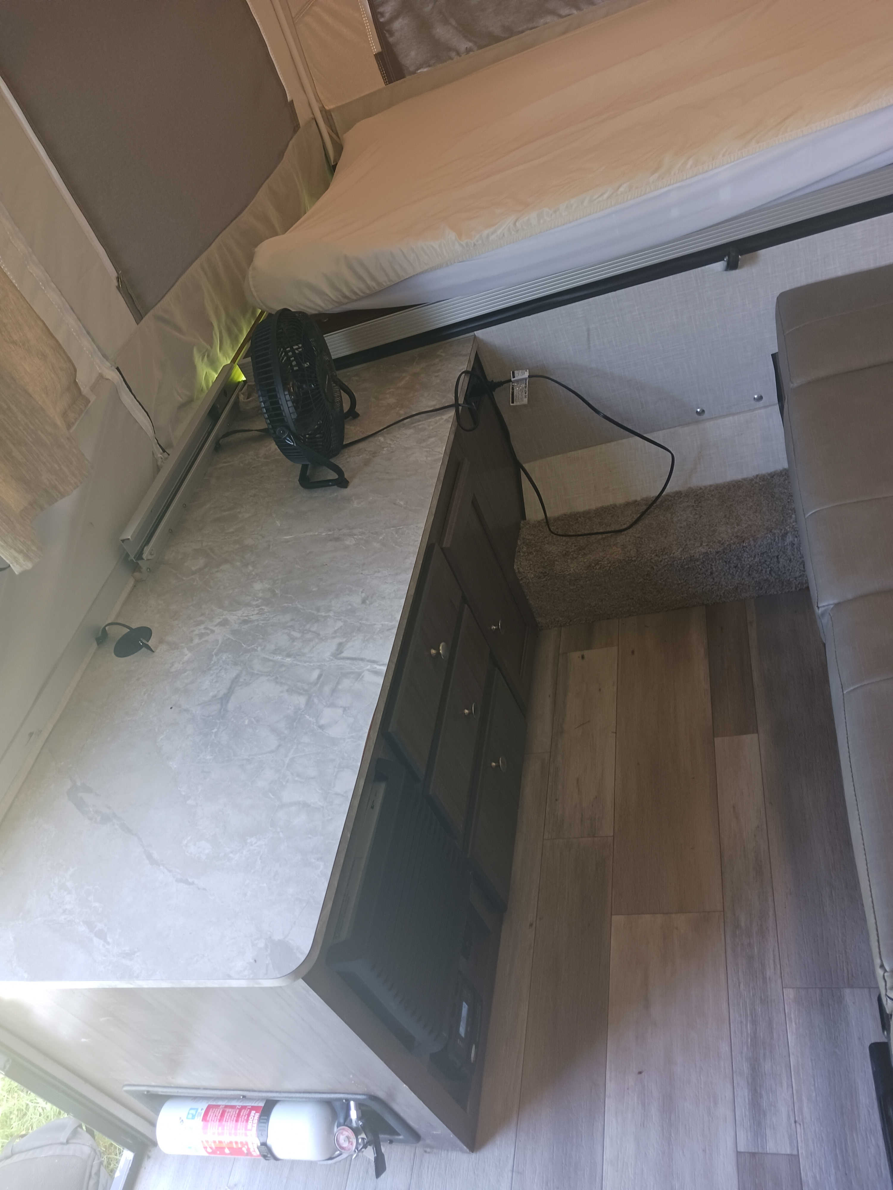 RV rental interior: view of a pop-up camper's bed, marbled counter with fan, and laminate flooring.. Forest River Rockwood Freedom 2022