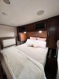 Spacious RV rental bedroom with queen bed, overhead cabinets, and TV, offering cozy comfort for your travels.. Jayco Jay Flight 2017