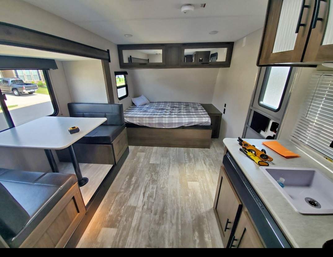 RV rental's interior showcasing a bed, dinette with table, and compact kitchen with sink. Perfect for travel!. Avenger LT 2021