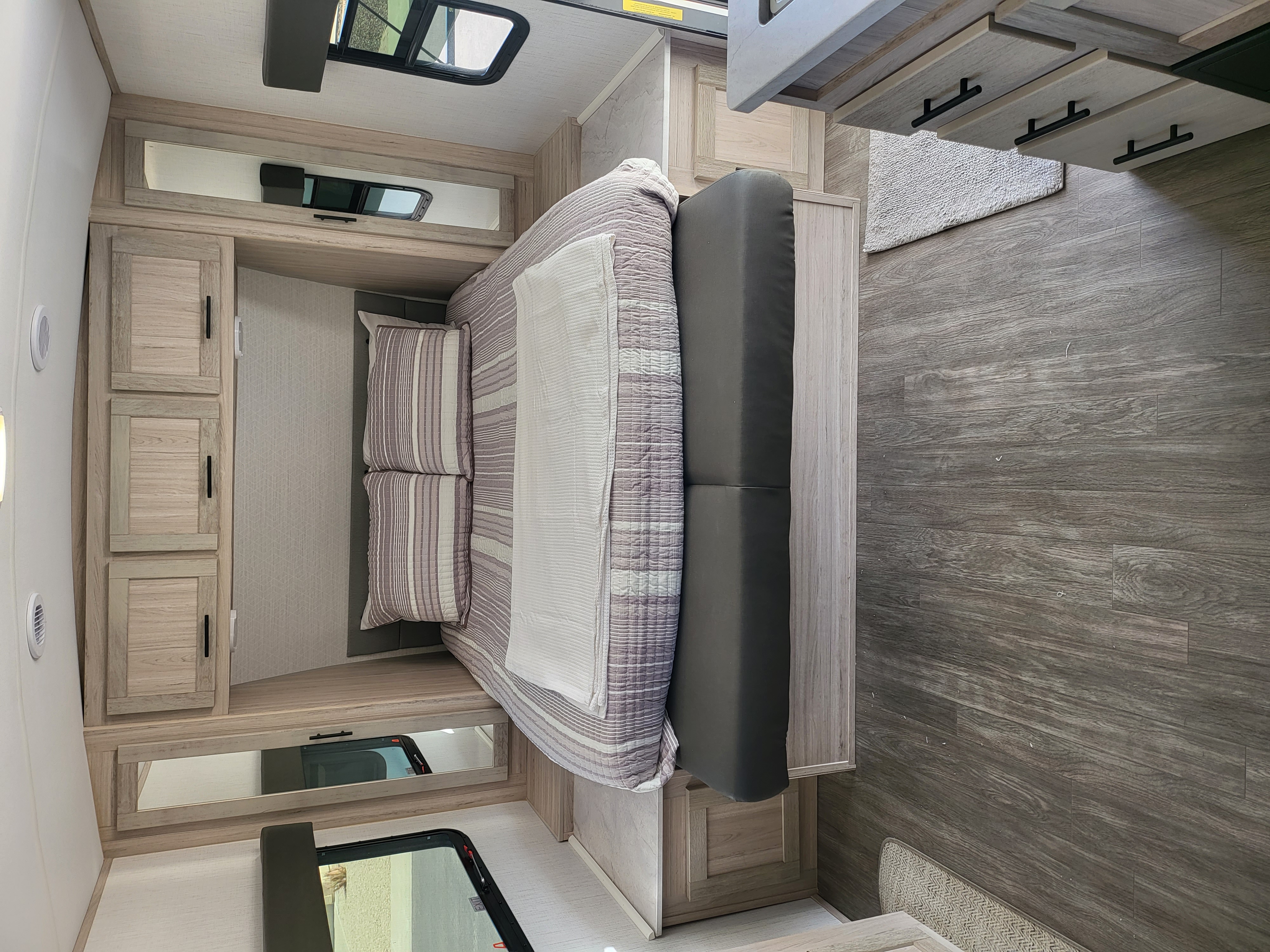 Inside this RV rental, a cozy bedroom with light wood cabinets, comfortable bedding, and wood-look flooring awaits your journey.. Cruiser RV Twilight Adventure 210 2022