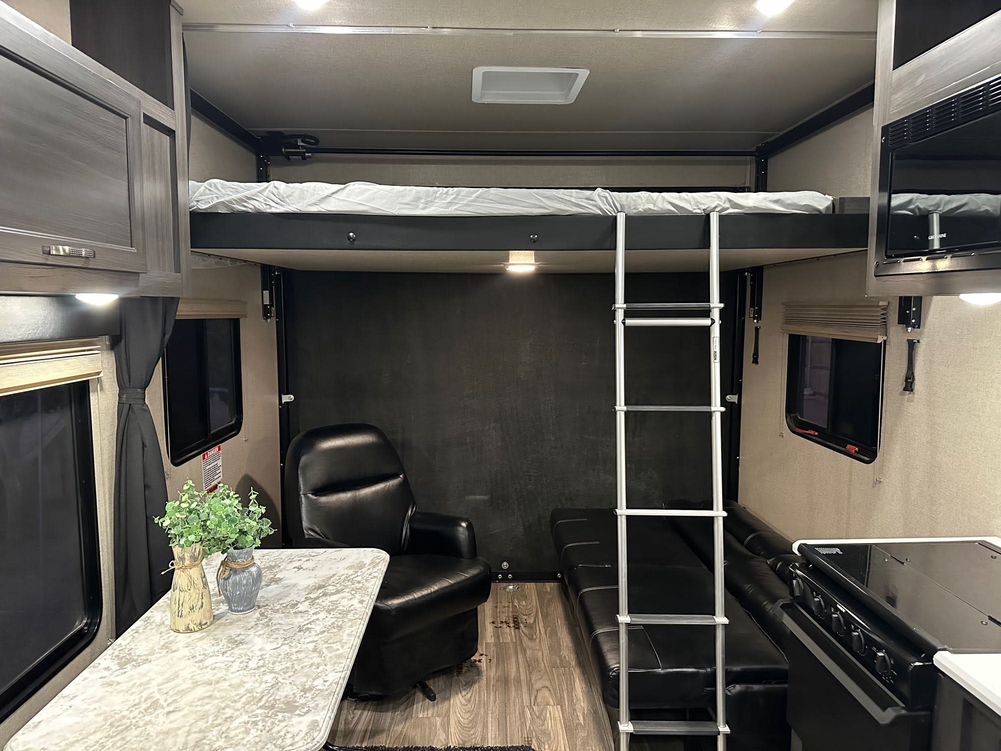 Well-equipped RV rental interior showcasing a bunk bed, kitchen, dining table, and cozy seating. Ready for adventure.. Genesis Supreme Wanderer 2021