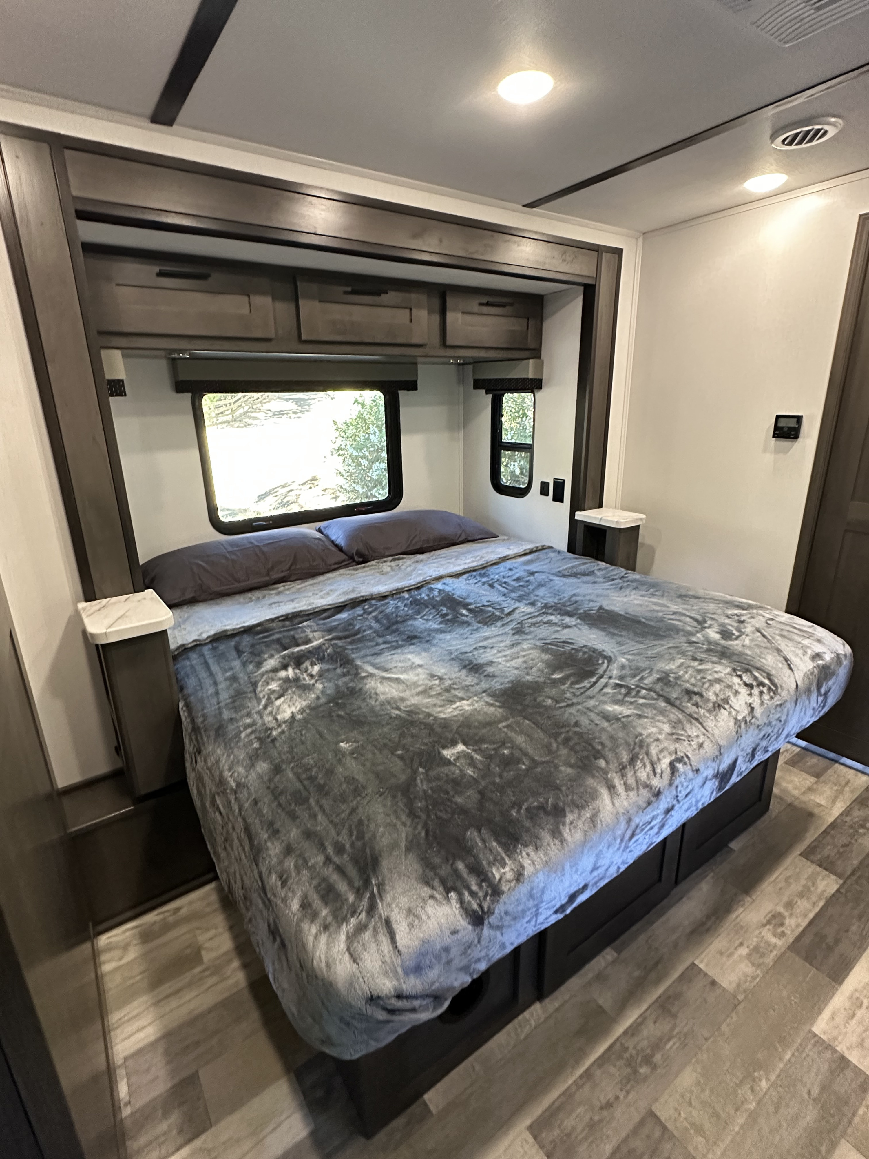 Experience comfort in this RV rental's cozy bedroom, featuring a large bed, overhead storage, and natural light from the windows.. FR3 FR3 Motorhome 2023