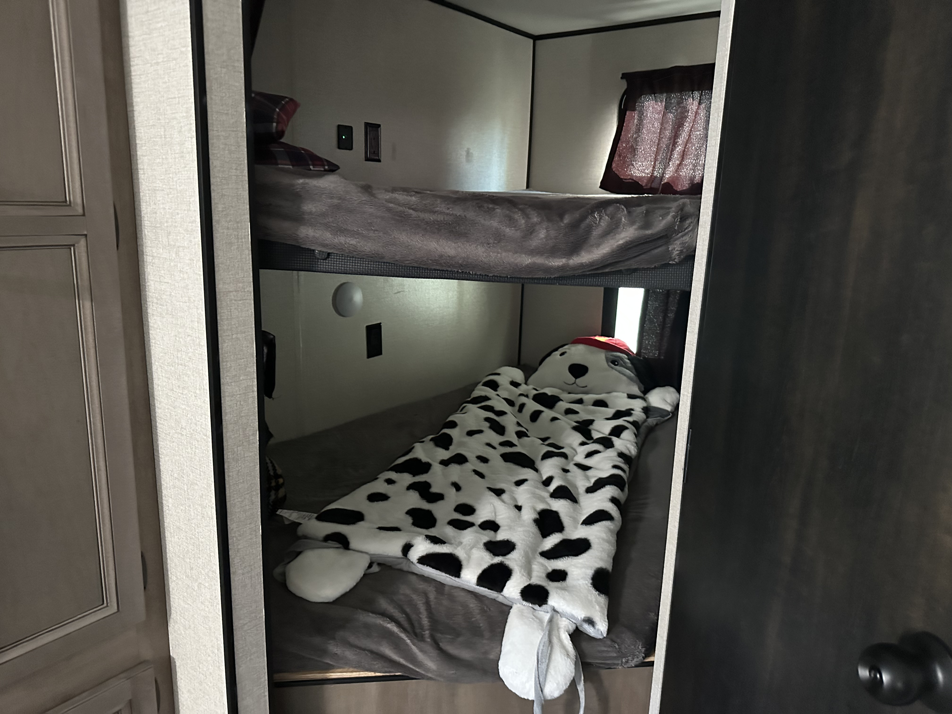 RV rental bunk beds feature a cozy upper bunk and a lower bunk with a cute dog-themed sleeping bag.. Starcraft Autumn Ridge 2022
