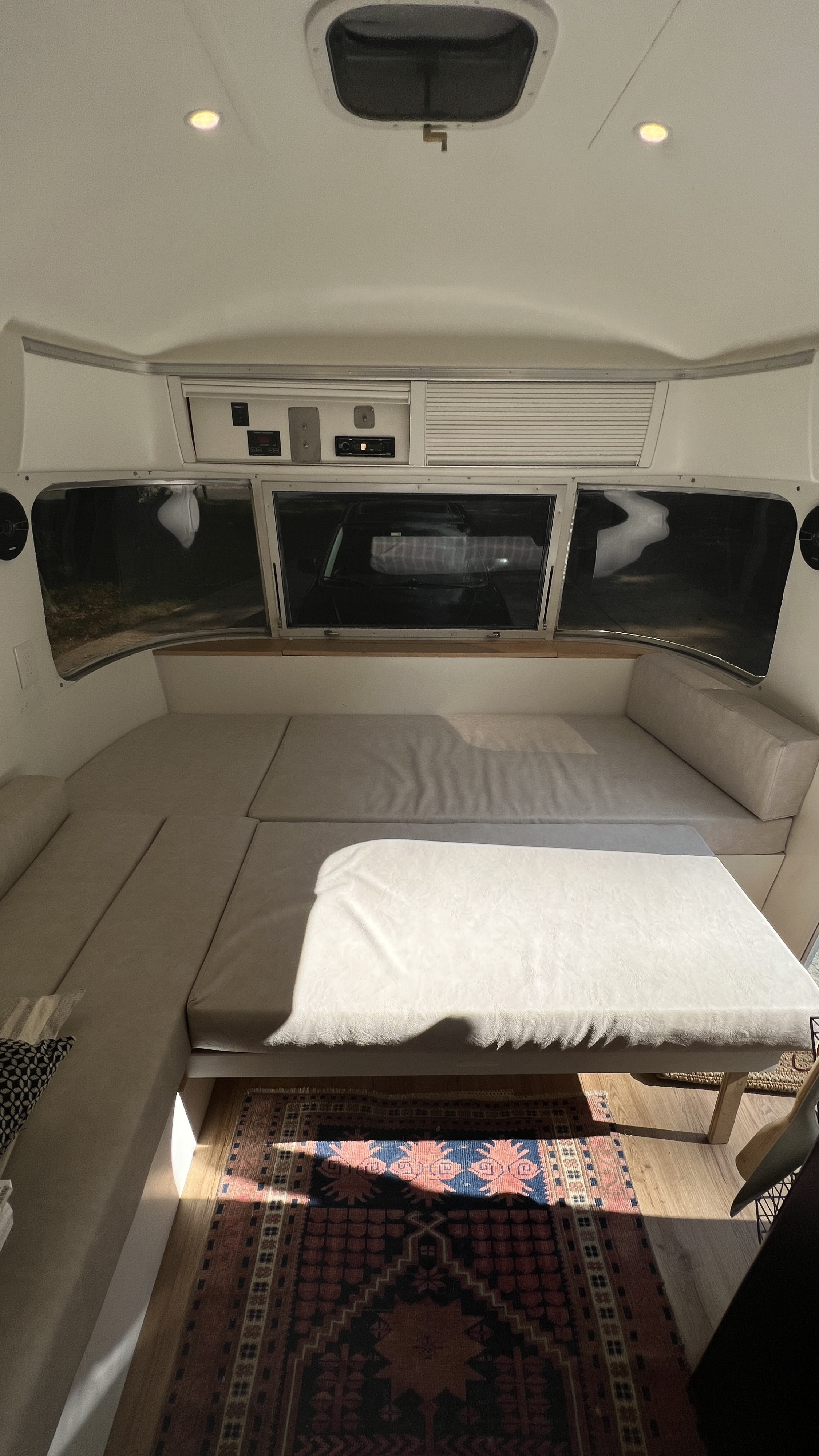 Inside this RV rental: light cushions create a convertible dinette/bed, featuring large windows, storage, and a cozy rug.. Airstream Argosy 1977