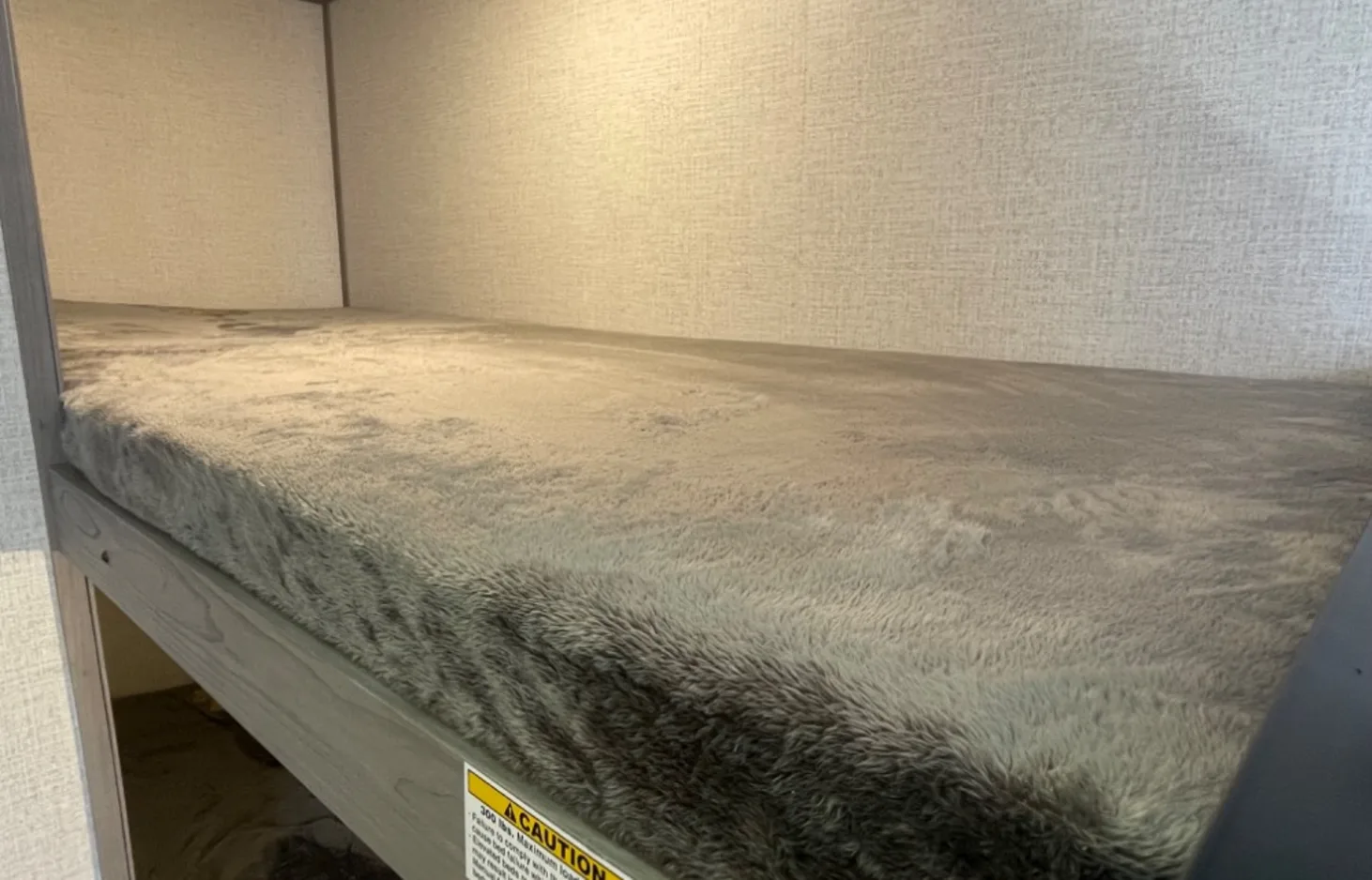 Upper bunk with soft grey mattress in an RV rental. Offers a cozy sleeping space for your next road trip.. Dutchmen Coleman Lantern LT 2023