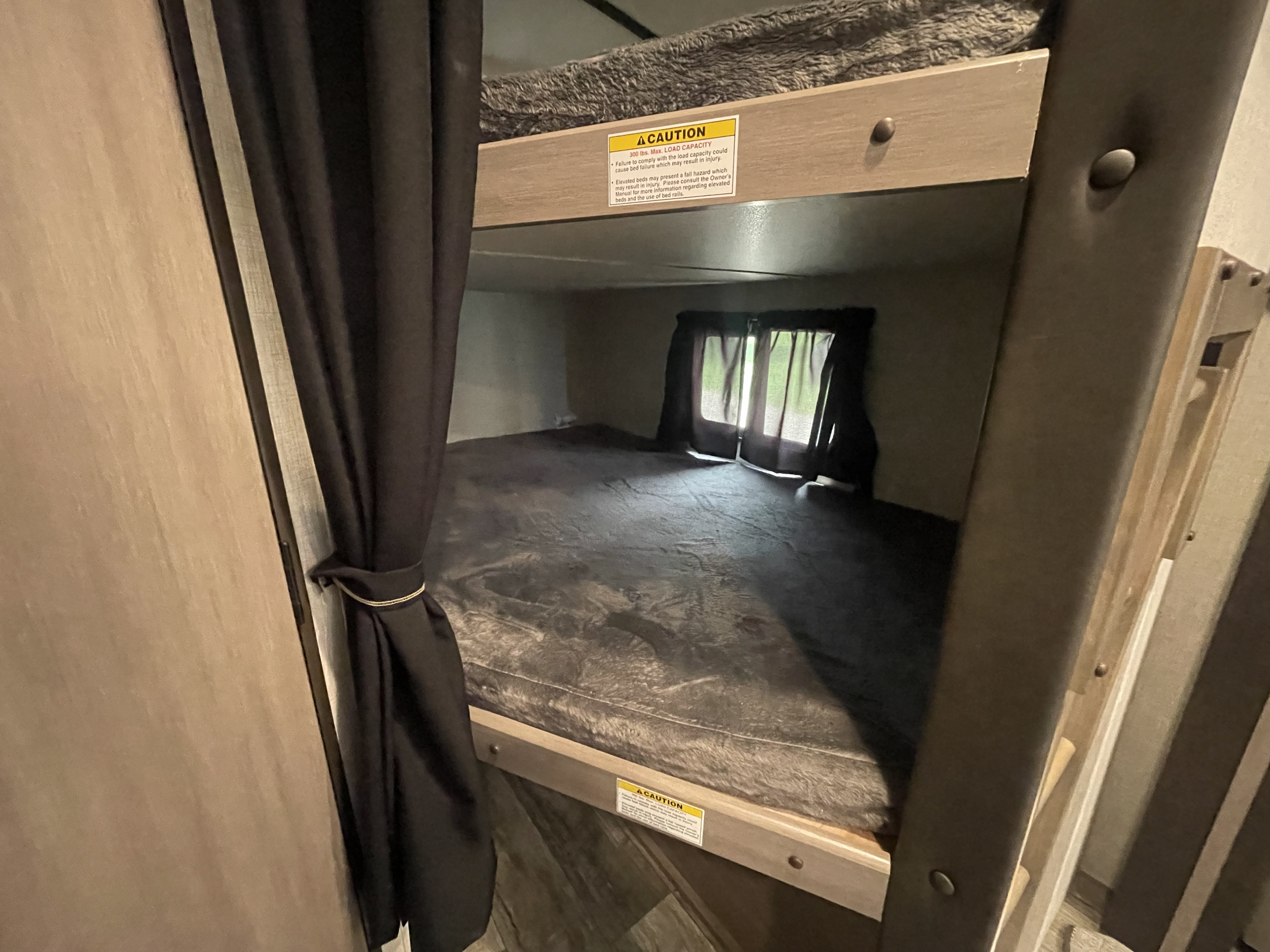RV rental interior featuring bunk beds with caution labels, providing a compact sleeping area for your travels.. Sunset Trail 272 BH 2022