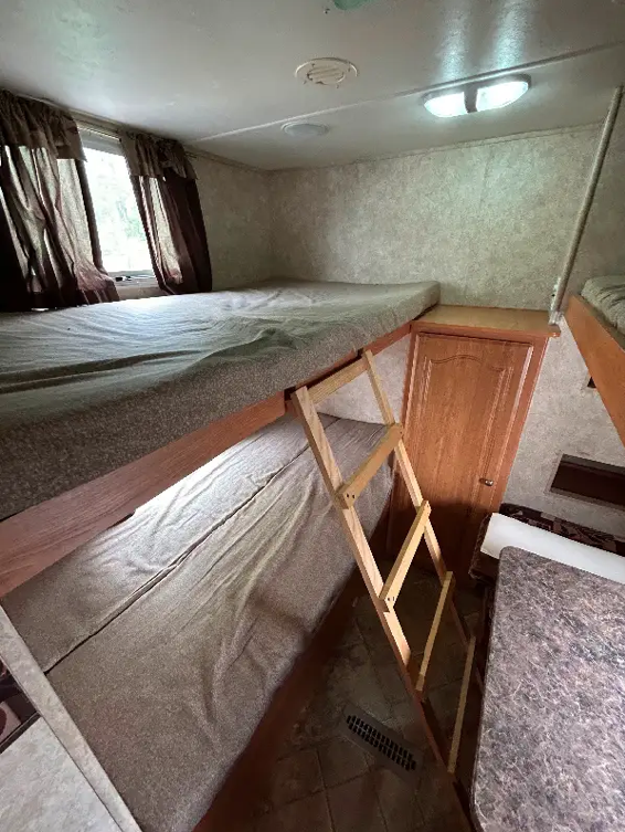 Experience comfort in this RV rental with double bunk beds, a ladder, and a cozy dinette setup.. Forest River Surveyor 2009