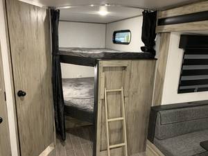 RV rental interior features comfortable bunk beds with a ladder, ideal for family camping trips. A window is visible near the top bunk.. Forest River Cherokee Alpha Wolf 2022