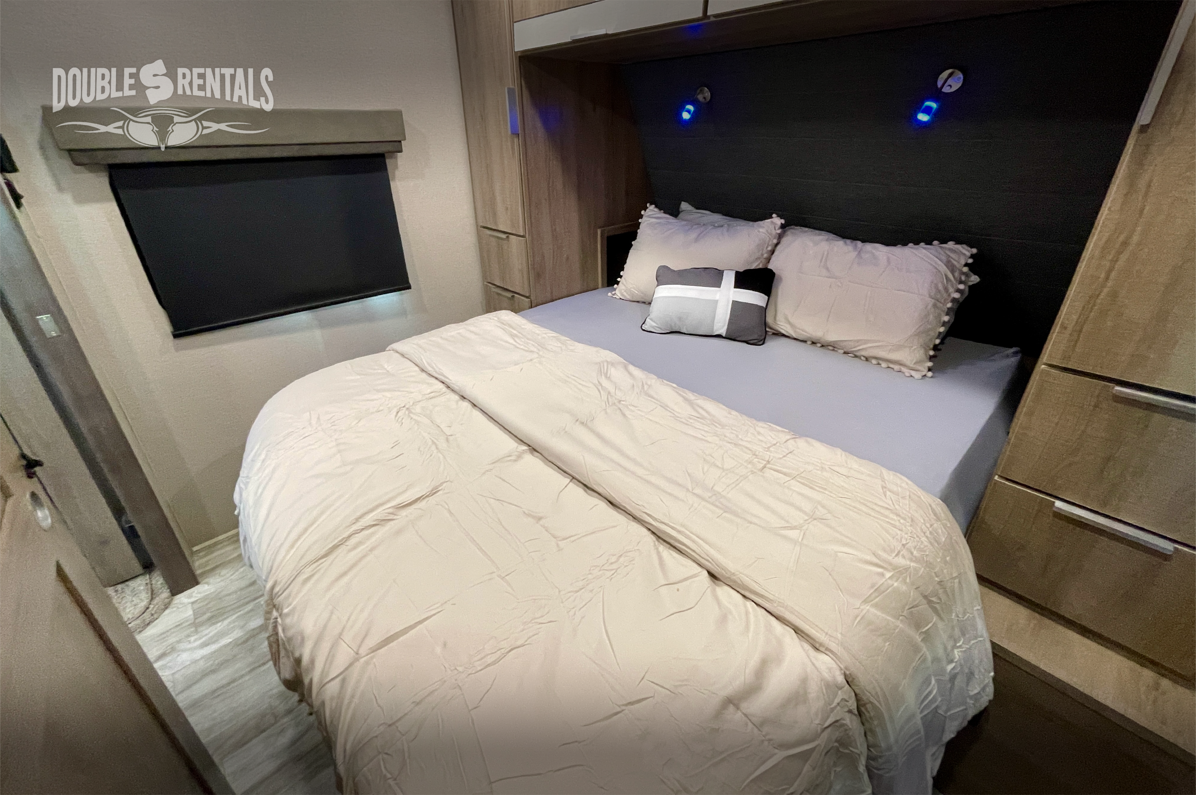 Cozy RV rental bedroom with a comfortable bed, built-in storage, and ambient blue reading lights. Perfect for relaxing.. Grand Design Imagine 2021