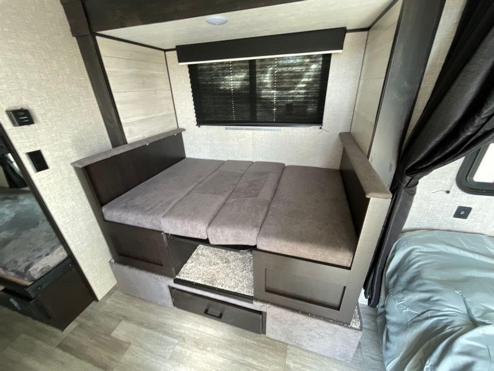 RV rental interior features a convertible dinette with storage, plus adjacent bed and bunk sleeping areas.. Jayco Jay Flight SLX Baja Edition 2023