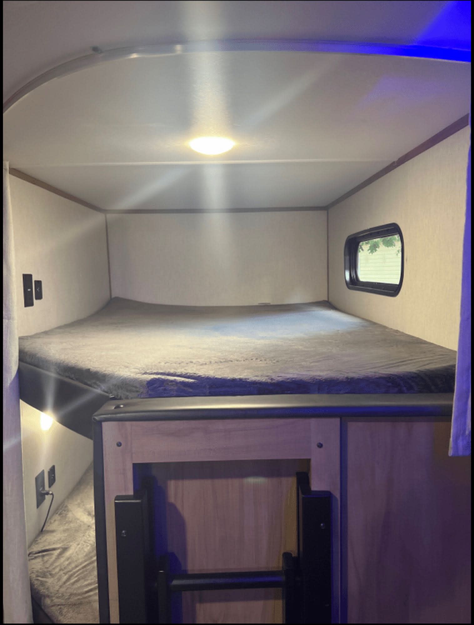 Inside an RV rental: a comfortable interior with upper and lower bunk beds, a window, and soft lighting.. Forest River Alpha Wolf 26-DBH-L 2023