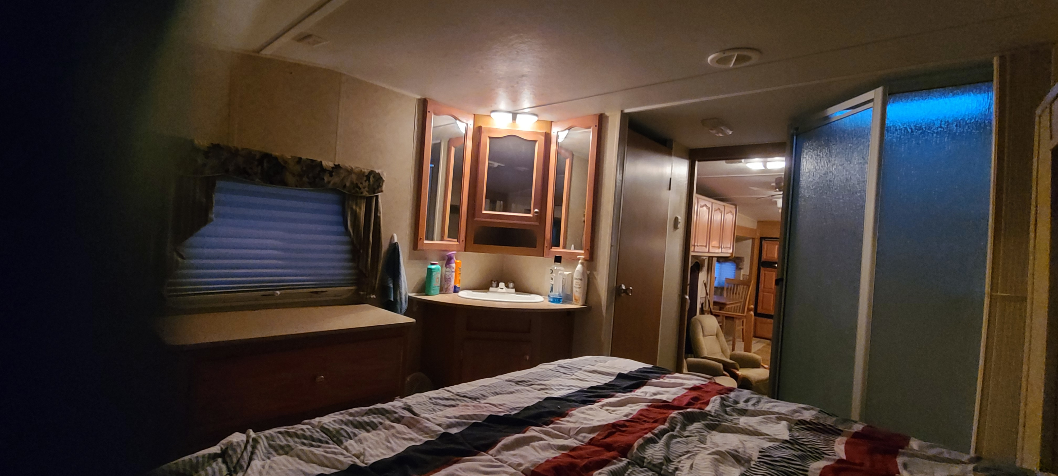 Cozy RV rental bedroom with a vanity, dresser, and view into the living space and shower. Ideal for travel.. Dutchmen Northshore 2007