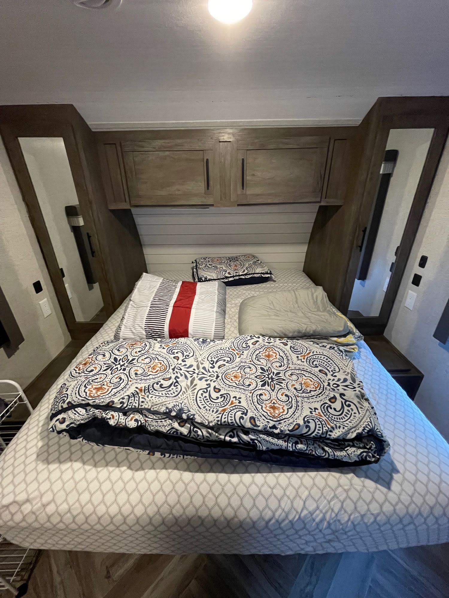 RV rental bedroom: cozy bed with stylish bedding, overhead storage, and bedside amenities for a comfortable stay.. Forest River Wildwood 2021