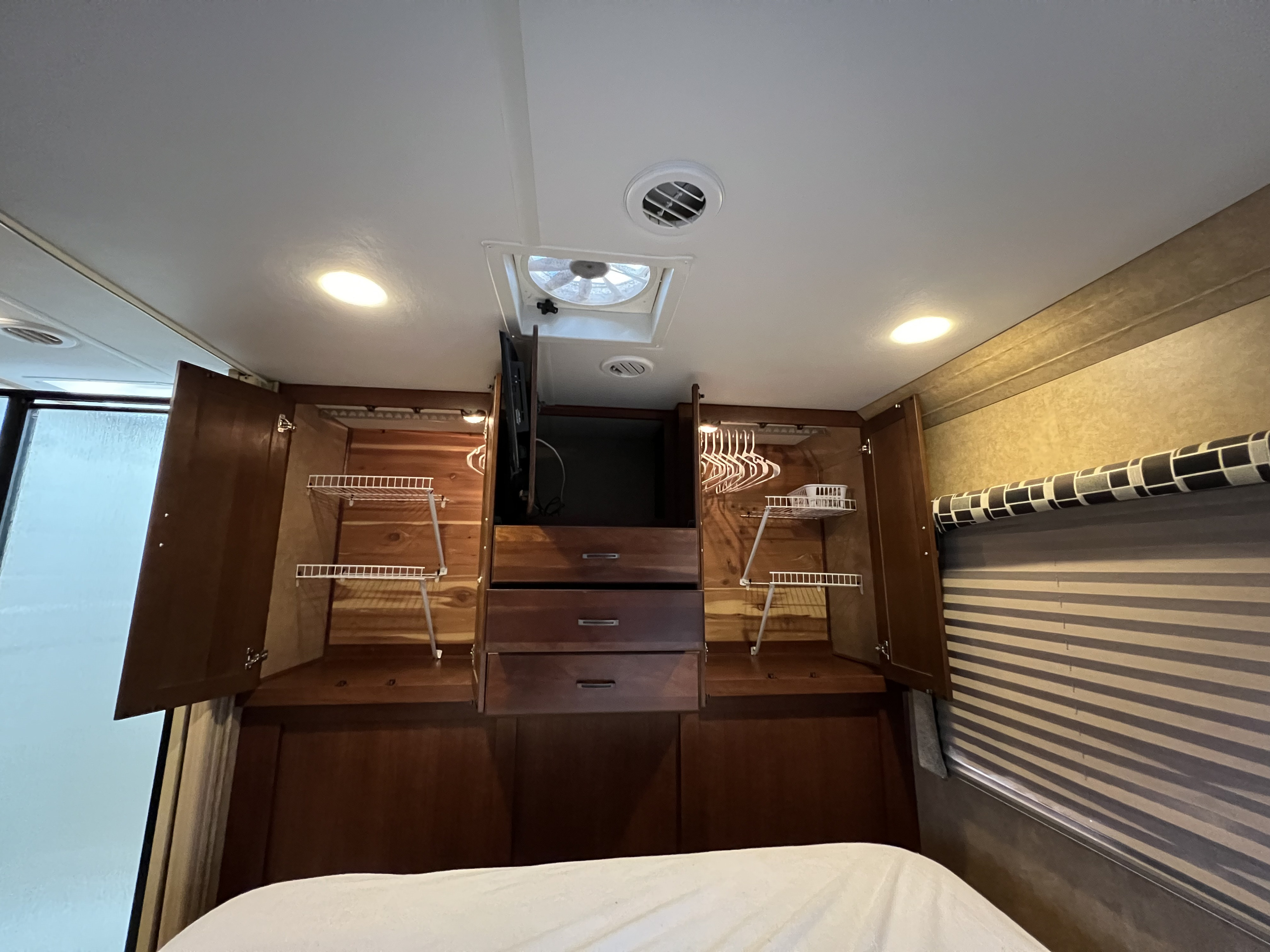 RV rental bedroom with extensive storage: open wooden wardrobes, drawers, TV, and overhead fan/vents.. Forest River Forester 2014