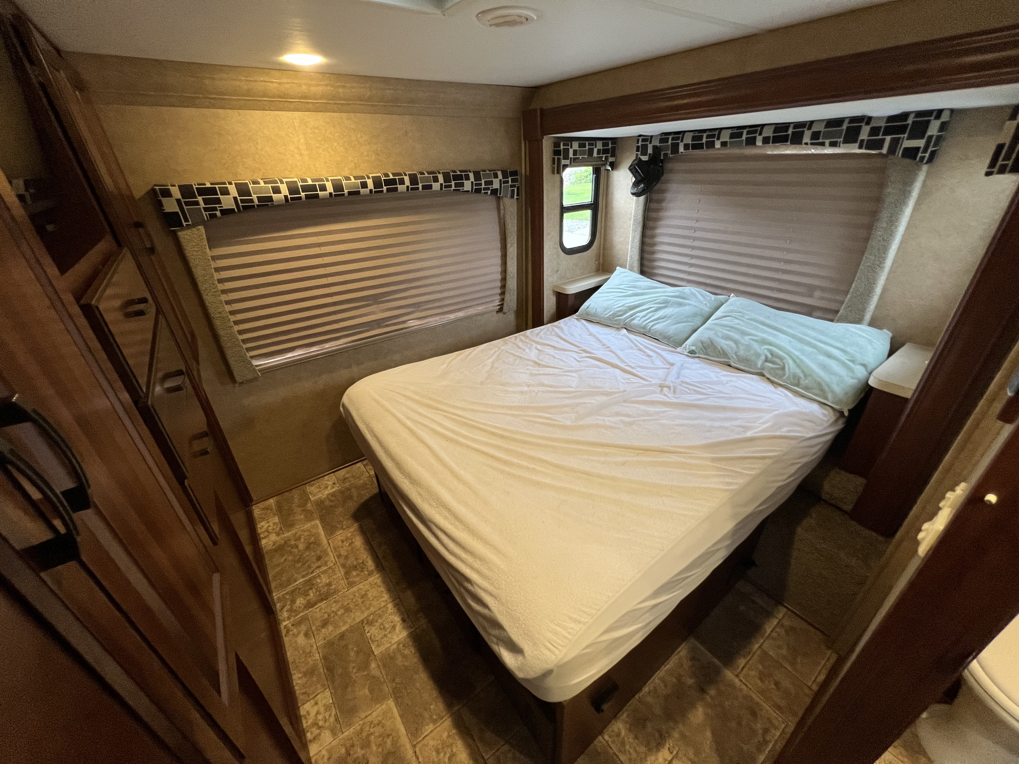 Comfortable RV rental bedroom with queen bed, window blinds, and built-in storage, perfect for travel accommodations.. Forest River Forester 2014