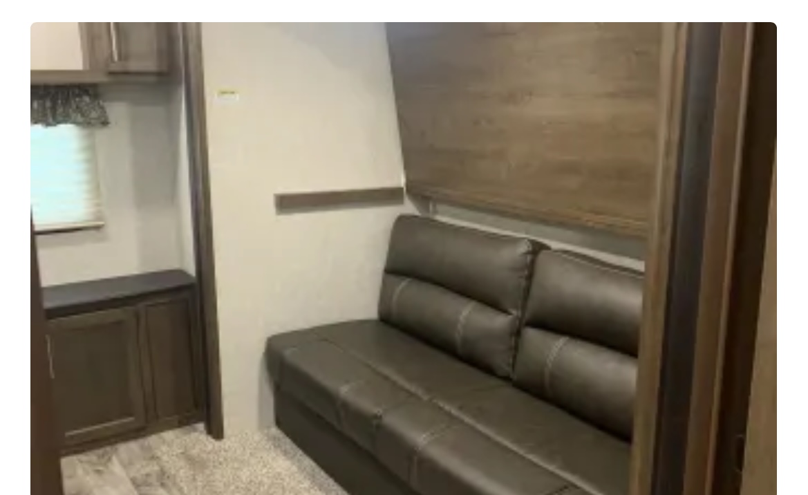 RV rental interior: A dark, convertible sofa, built-in cabinet, and window blinds in a compact living area.. Keystone RV Cougar 2019