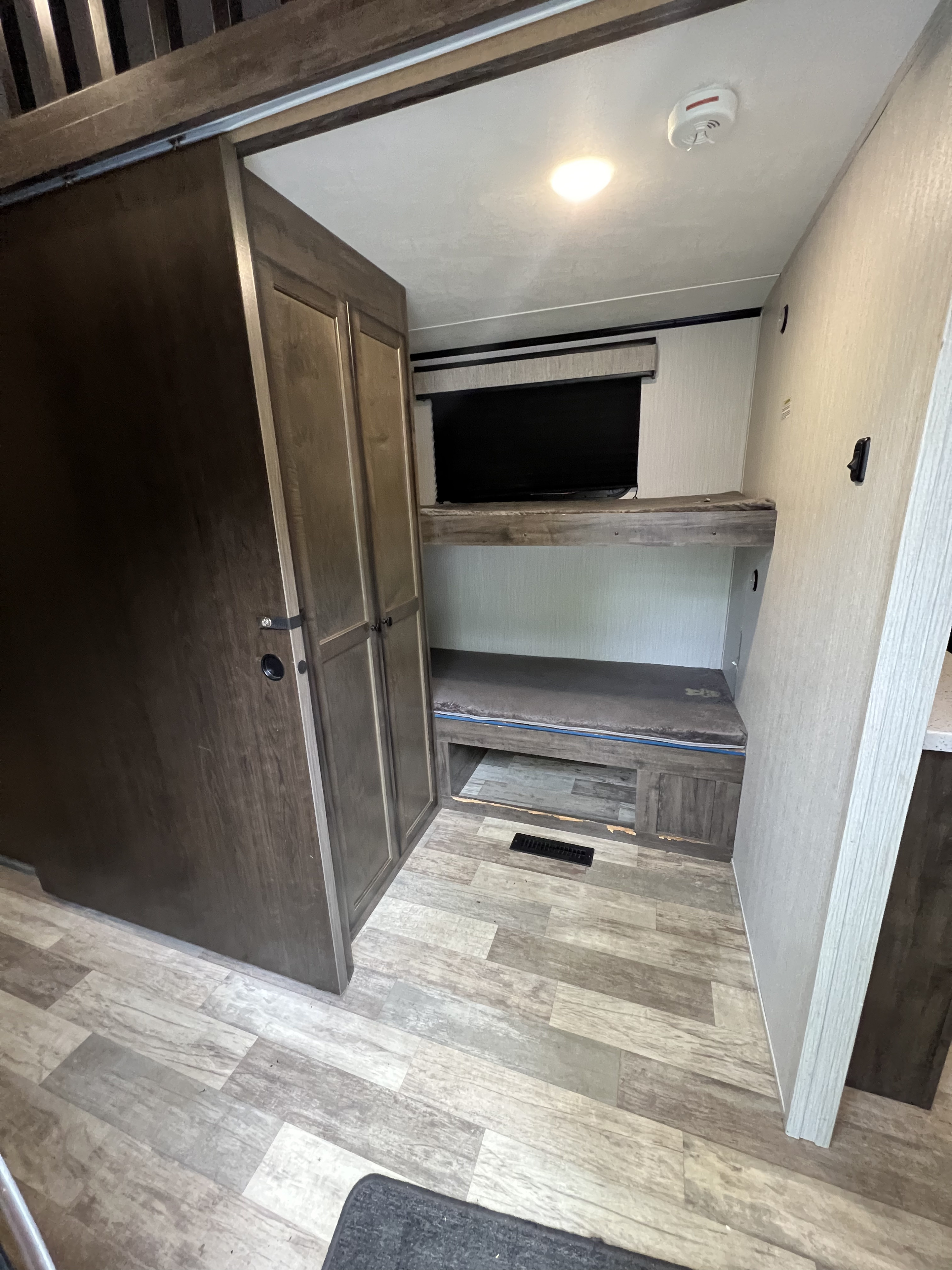 RV rental bunk area with TV, closet, and floor vent. Compact, functional sleeping and storage space.. Heartland RVs Milestone 2020