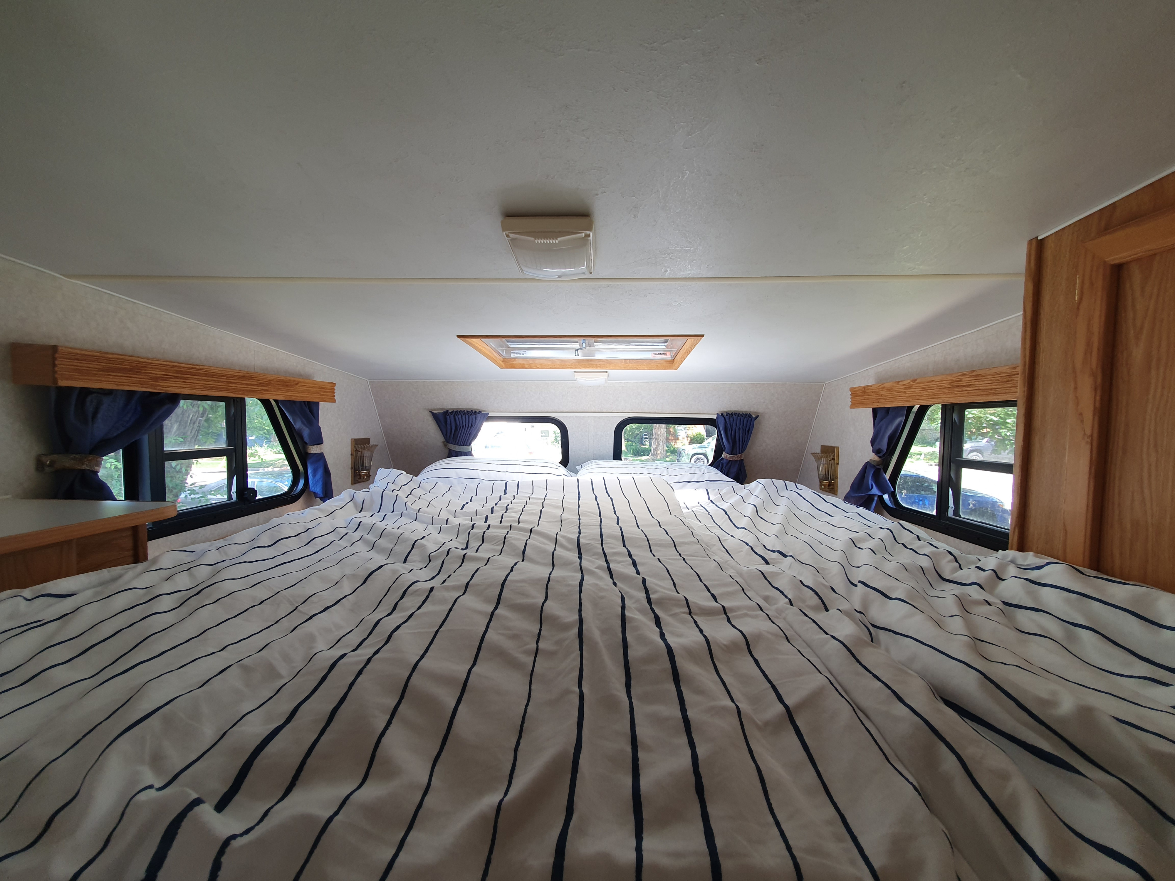 RV rental bedroom interior: large bed with striped linens, bright windows. A cozy sleeping space.. Northstar Laredo Sc 2004