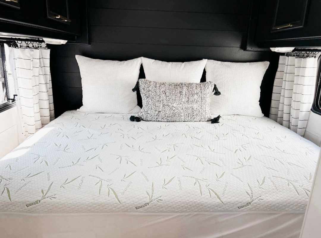RV rental bedroom: cozy space with bamboo mattress, white pillows, black shiplap wall, and striped curtains.. Terry Fleetwood 1991