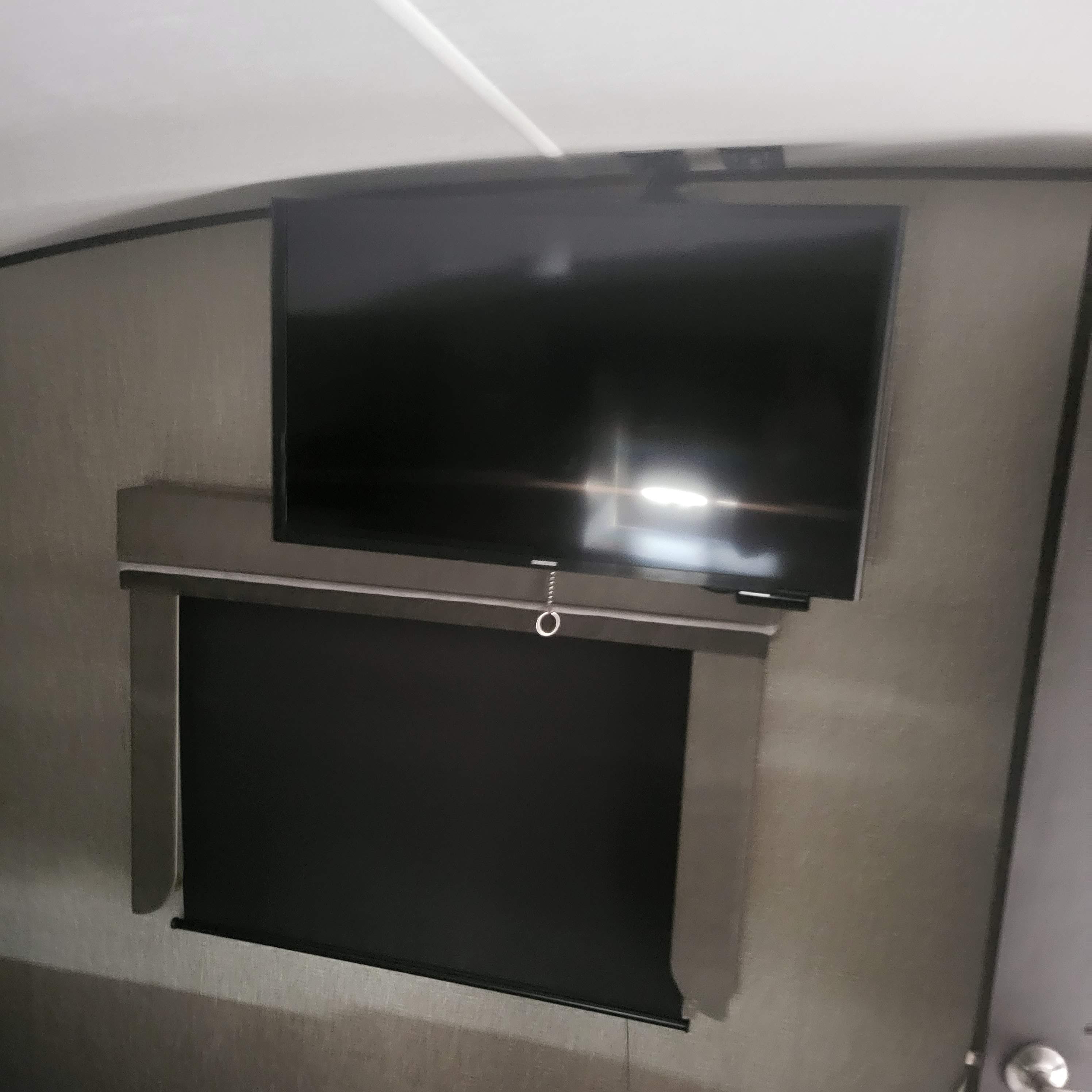 RV rental interior: A wall-mounted TV is positioned above a dark window shade, maximizing space in this compact living area.. Grand Design Reflection 2020