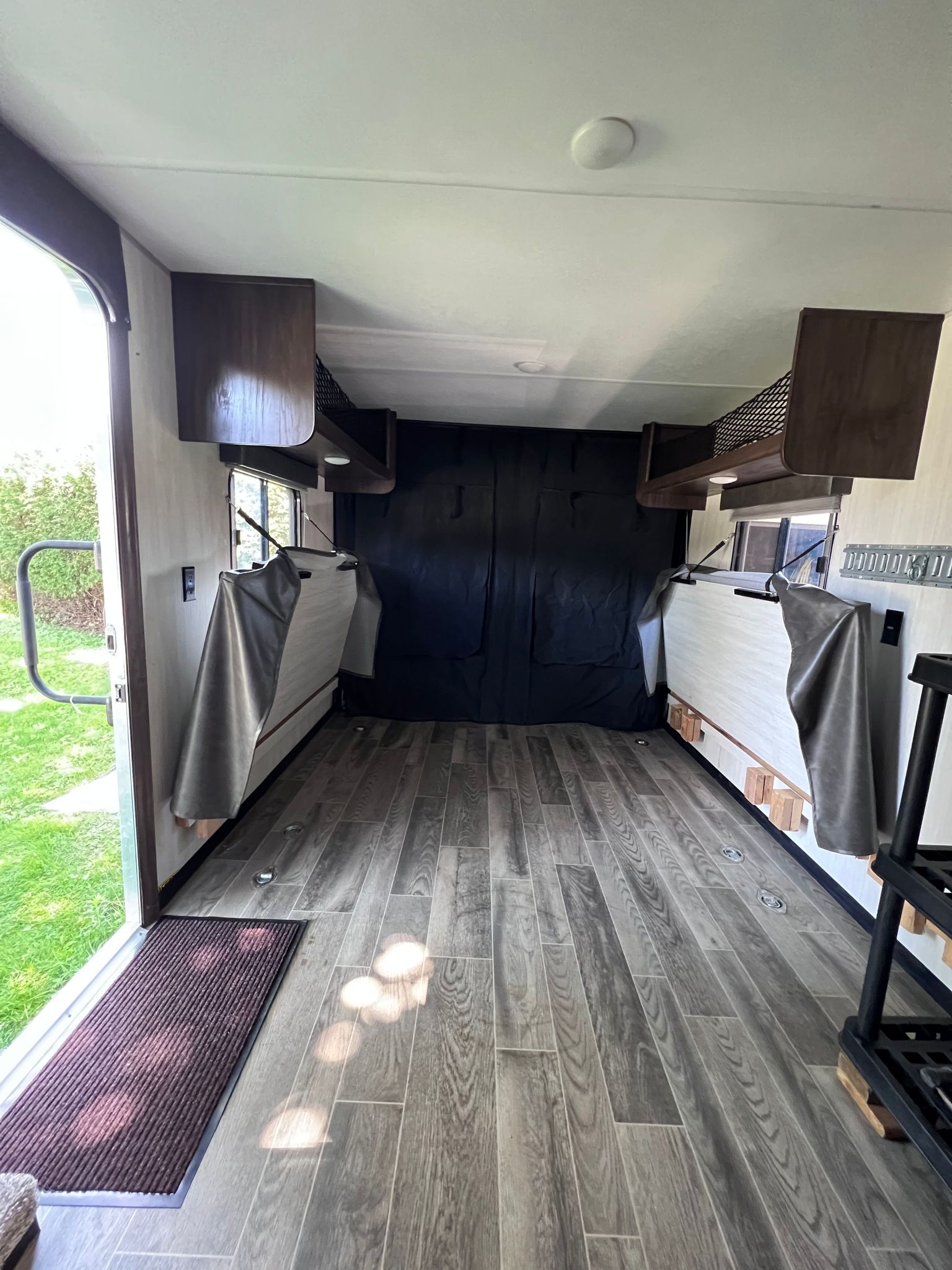 Spacious RV rental interior: wood-look floor, fold-up beds, overhead storage, and open door. Versatile camper utility space.. Forest River Cherokee Grey Wolf 2019