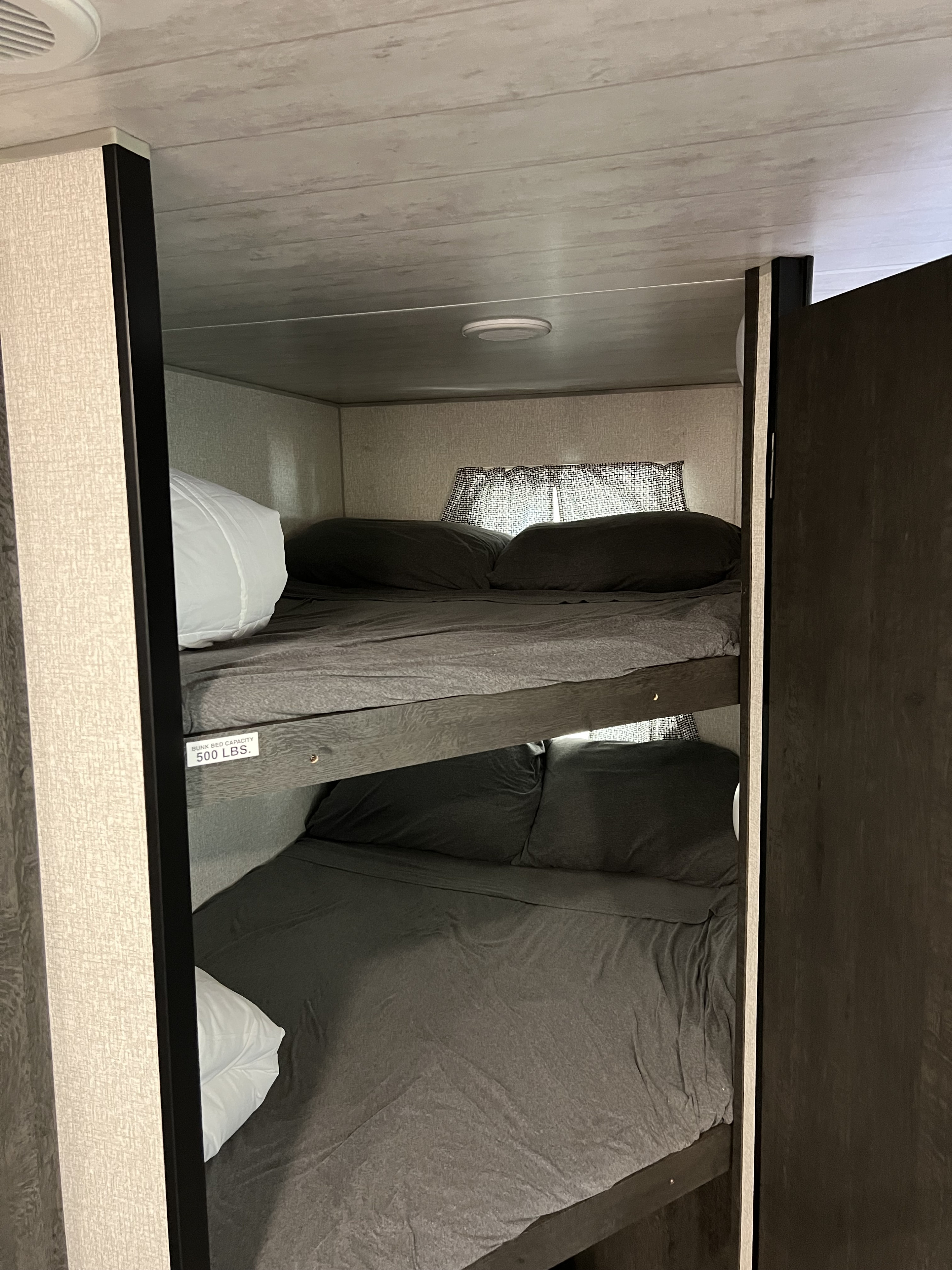 Inside an RV rental, comfortable bunk beds with gray bedding and a 500 lbs capacity label offer cozy sleeping arrangements.. KZ 271BHKSE 2022