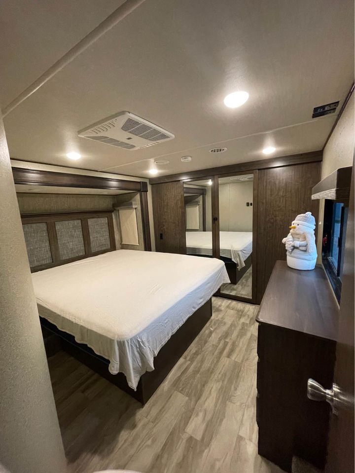 Spacious RV rental bedroom featuring a large bed, mirrored closets, and a dresser, offering a comfortable interior.. Grand Design Solitude 2019