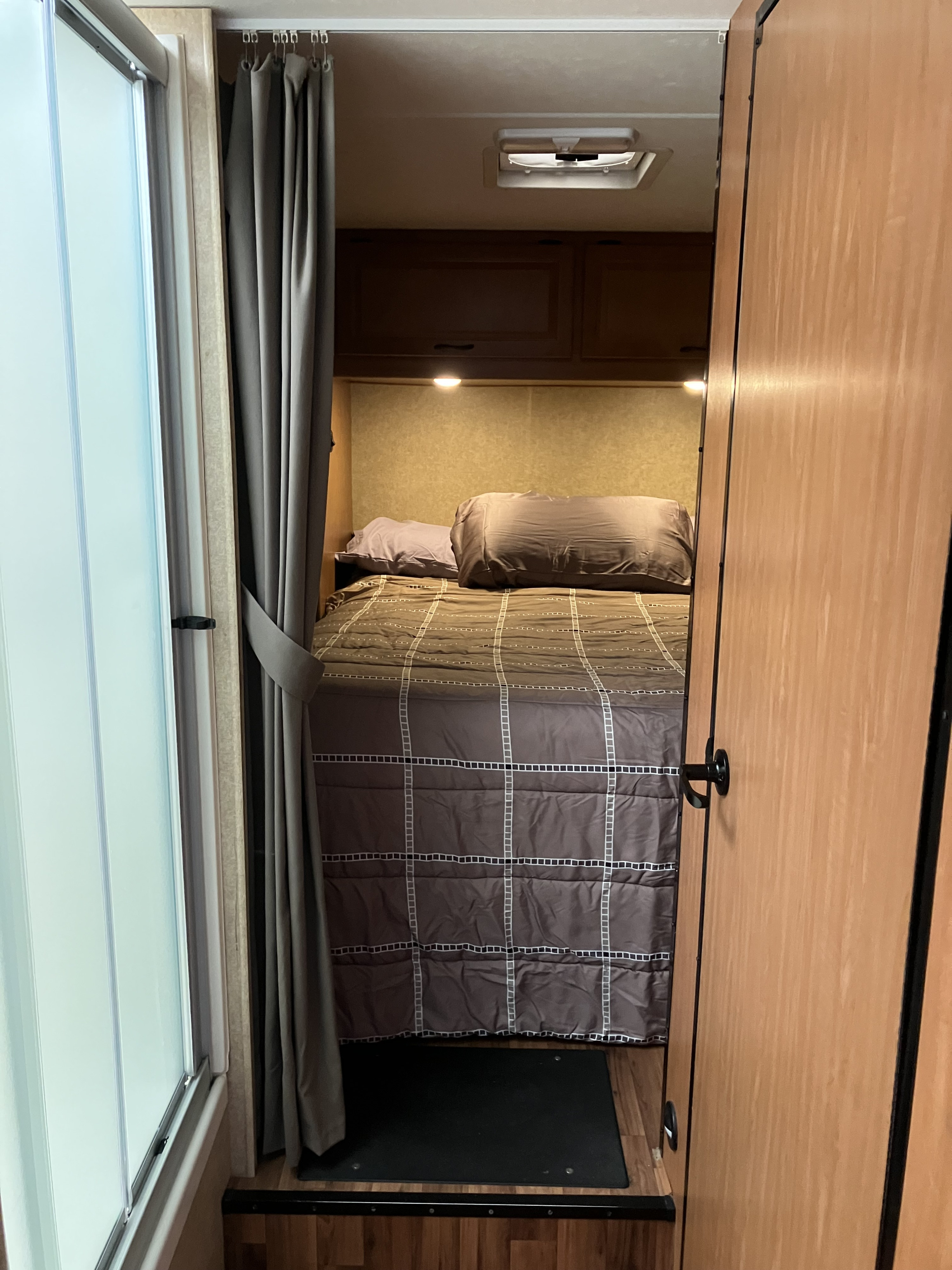 RV rental bedroom: compact space with bed, overhead storage, privacy curtain, and adjacent shower.. Majestic Ford 2018