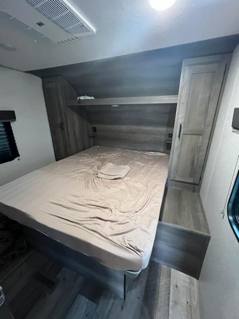 Comfortable RV rental bedroom featuring a large bed with light sheets, built-in storage, and ceiling AC.. Sportsmen SE 2021